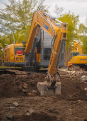 A yellow excavator digging in dirt at a construction site.