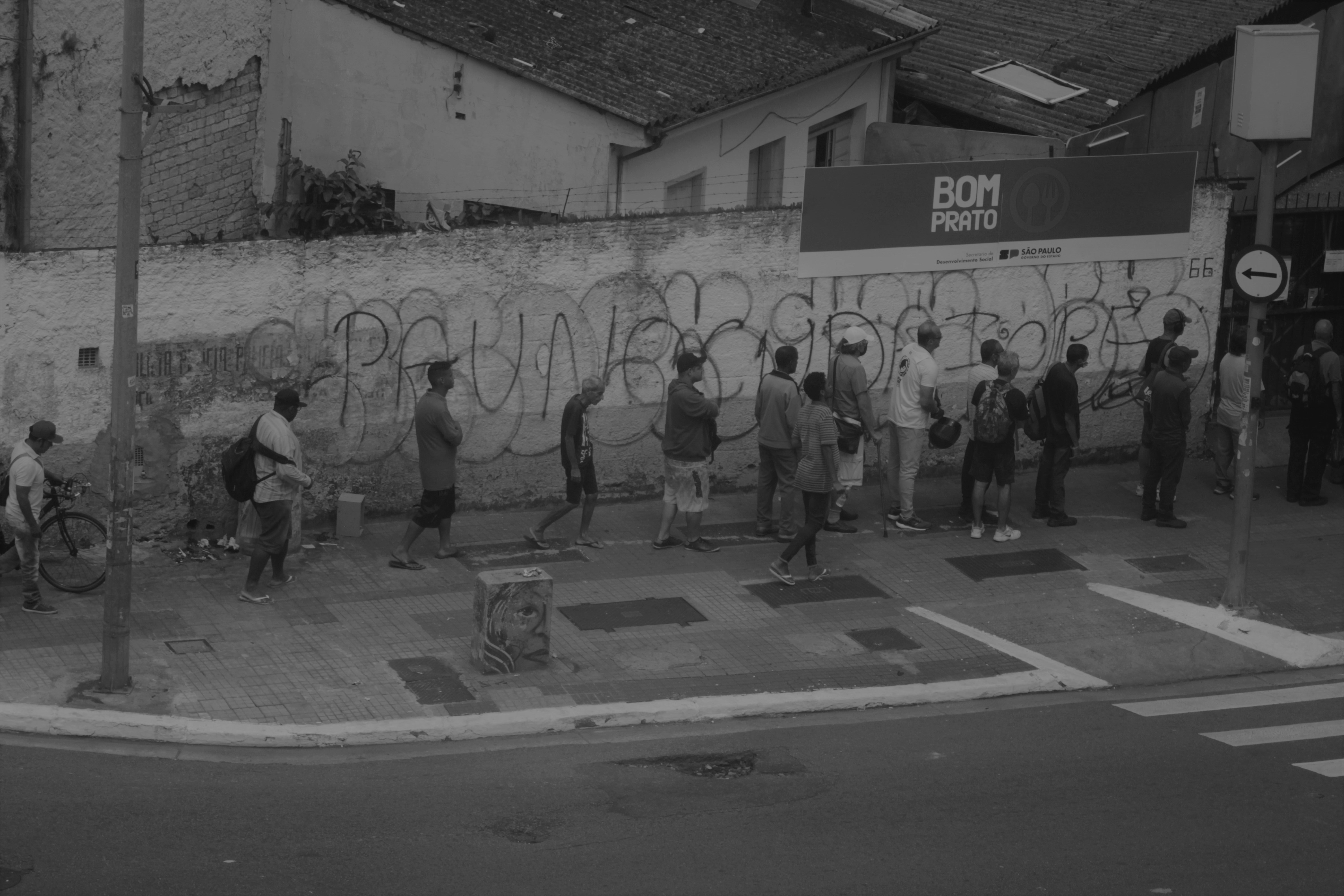 Urban street corner with people waiting by a graffiti wall.