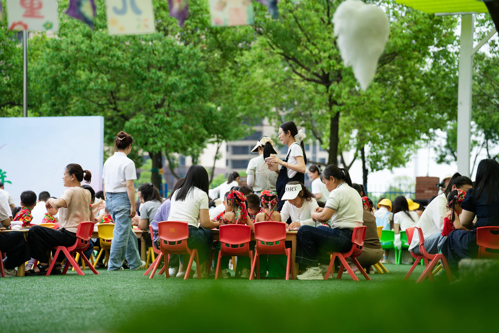 Families and children gathered at tables in a green park near the campus