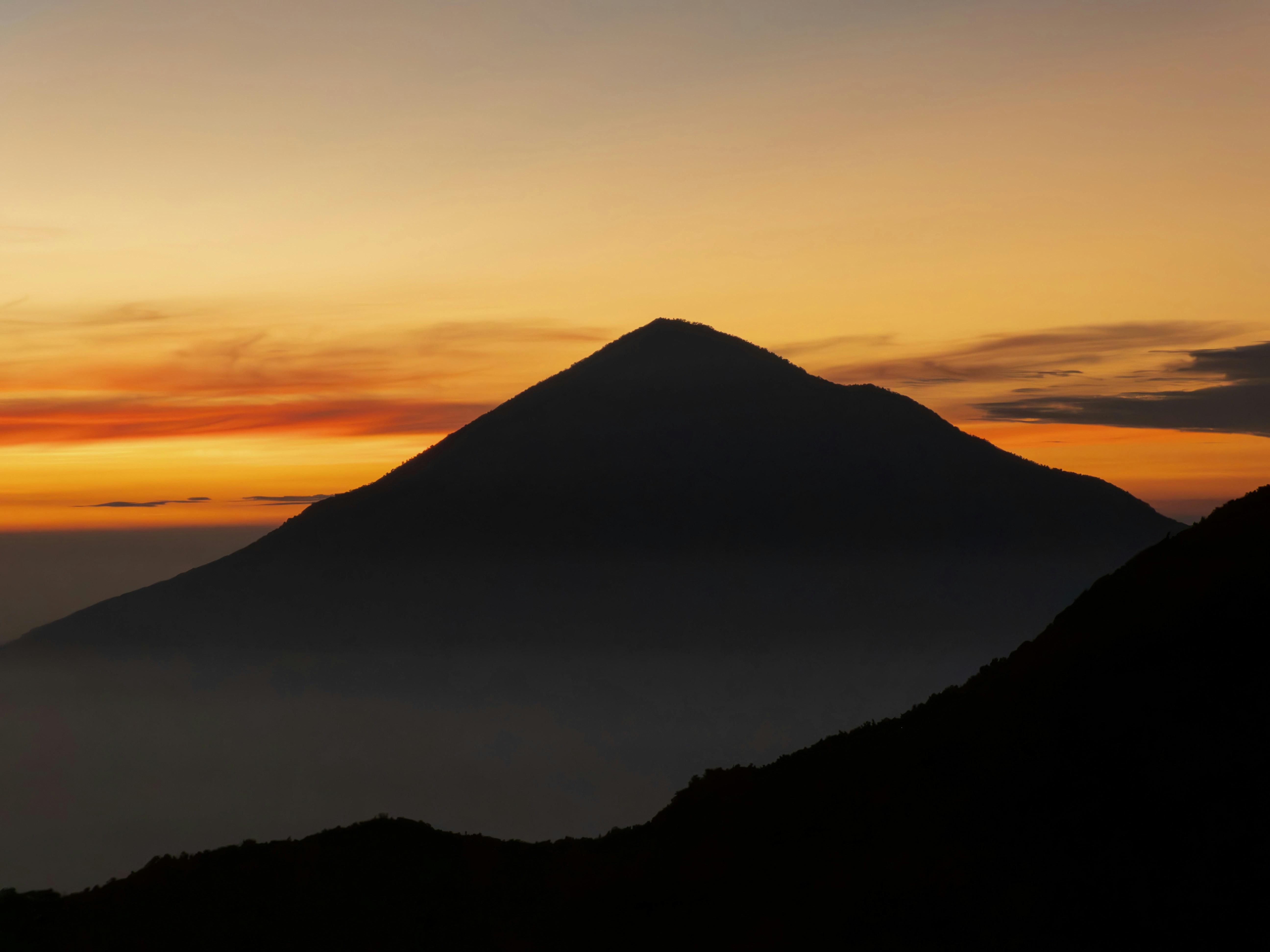 Dark mountain silhouette against a beautiful orange and yellow sunset