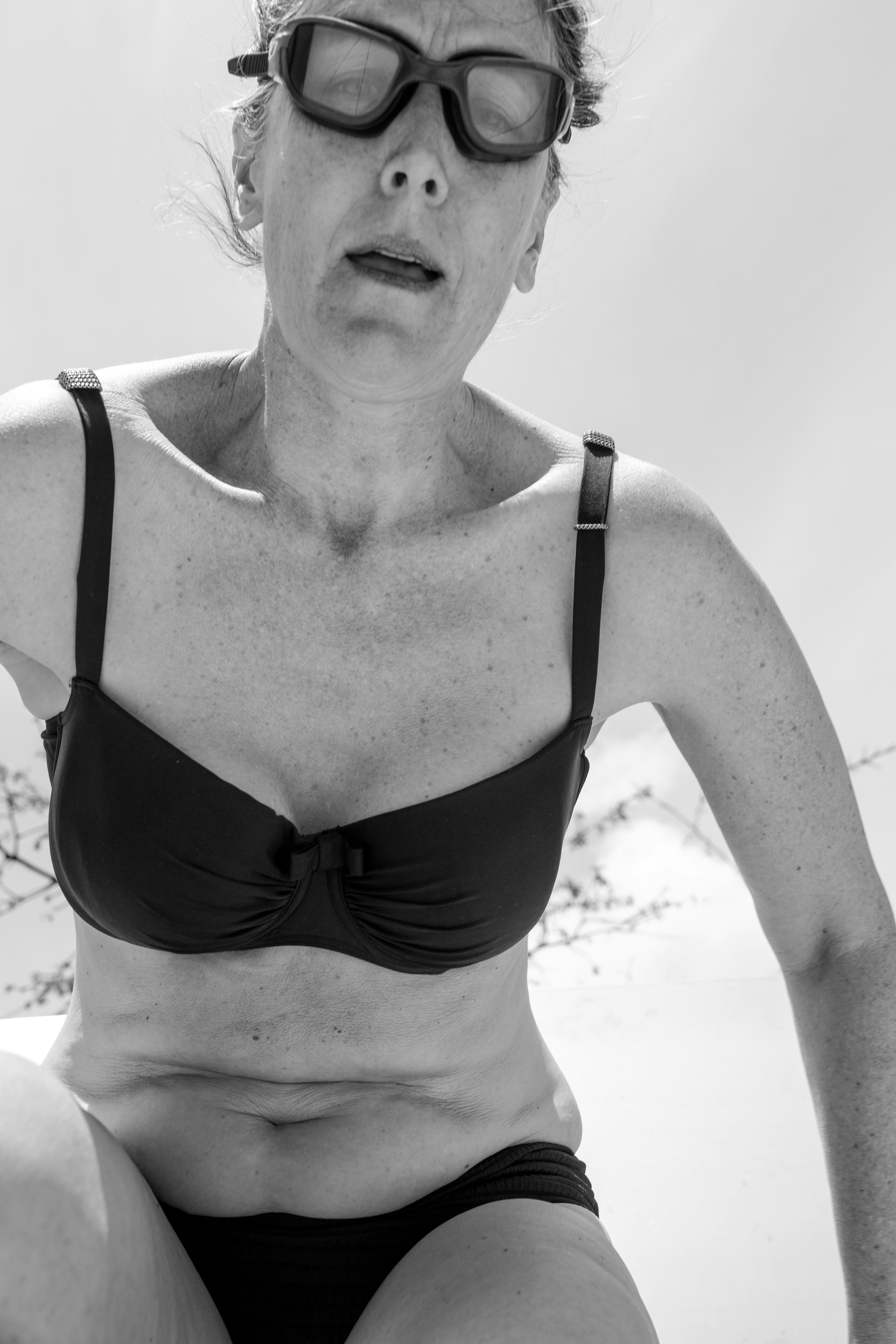 Woman in bikini and swim goggles looking down