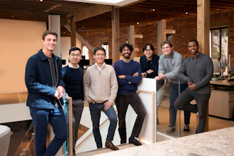 Seven diverse men standing together in a modern office