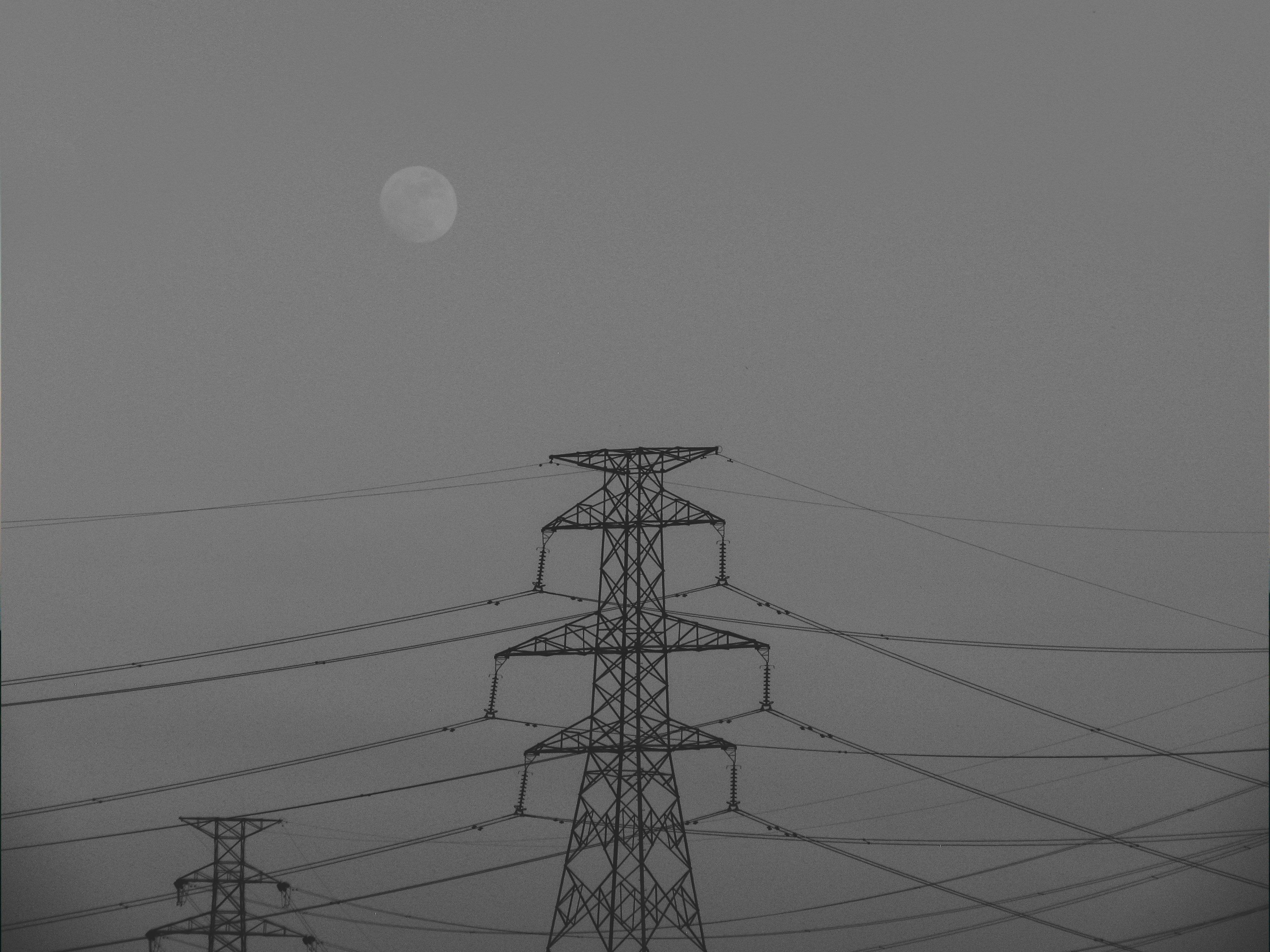 Grayscale moon and power transmission tower.