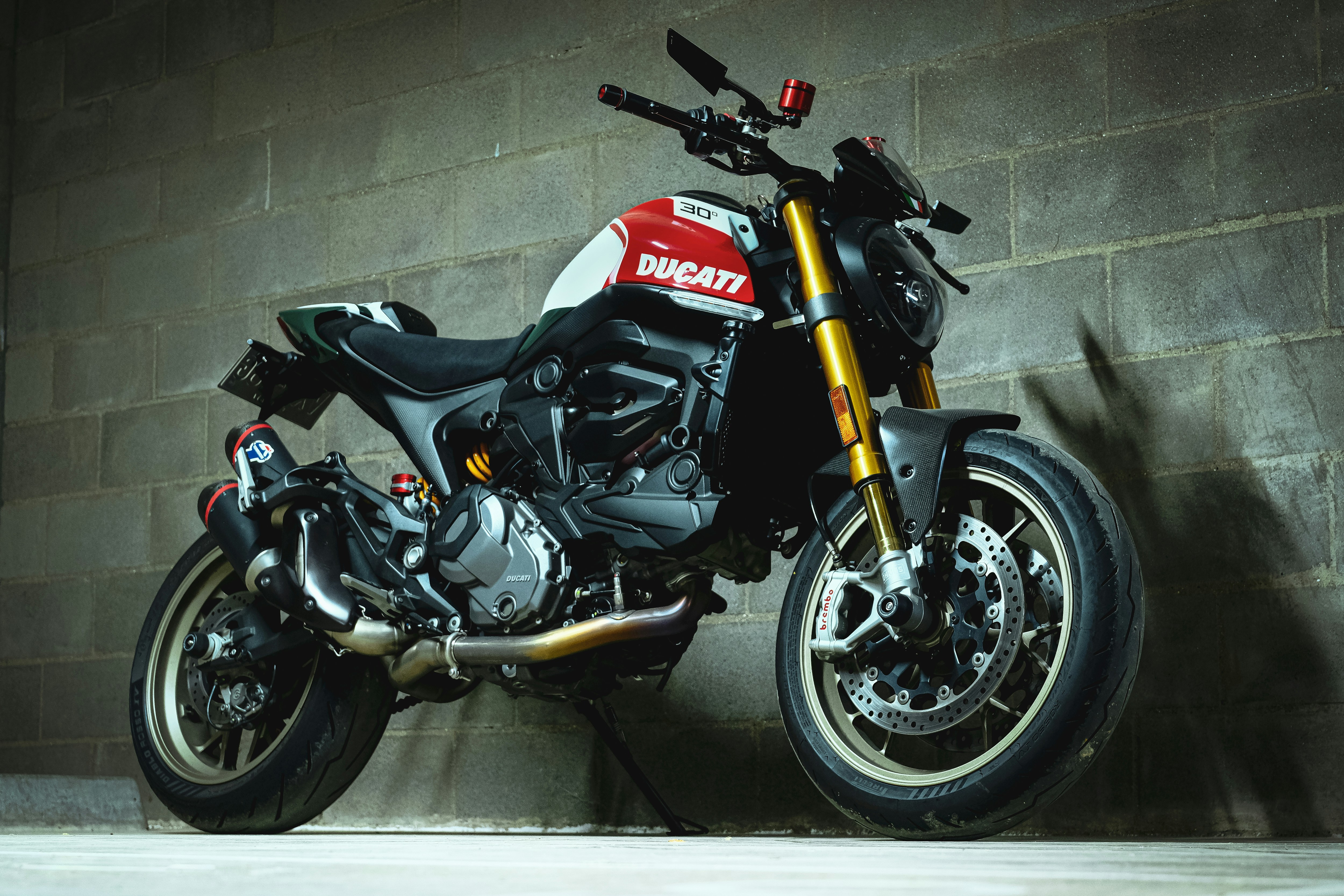 Una motocicleta Ducati roja y blanca aparcada contra un muro de hormigón.