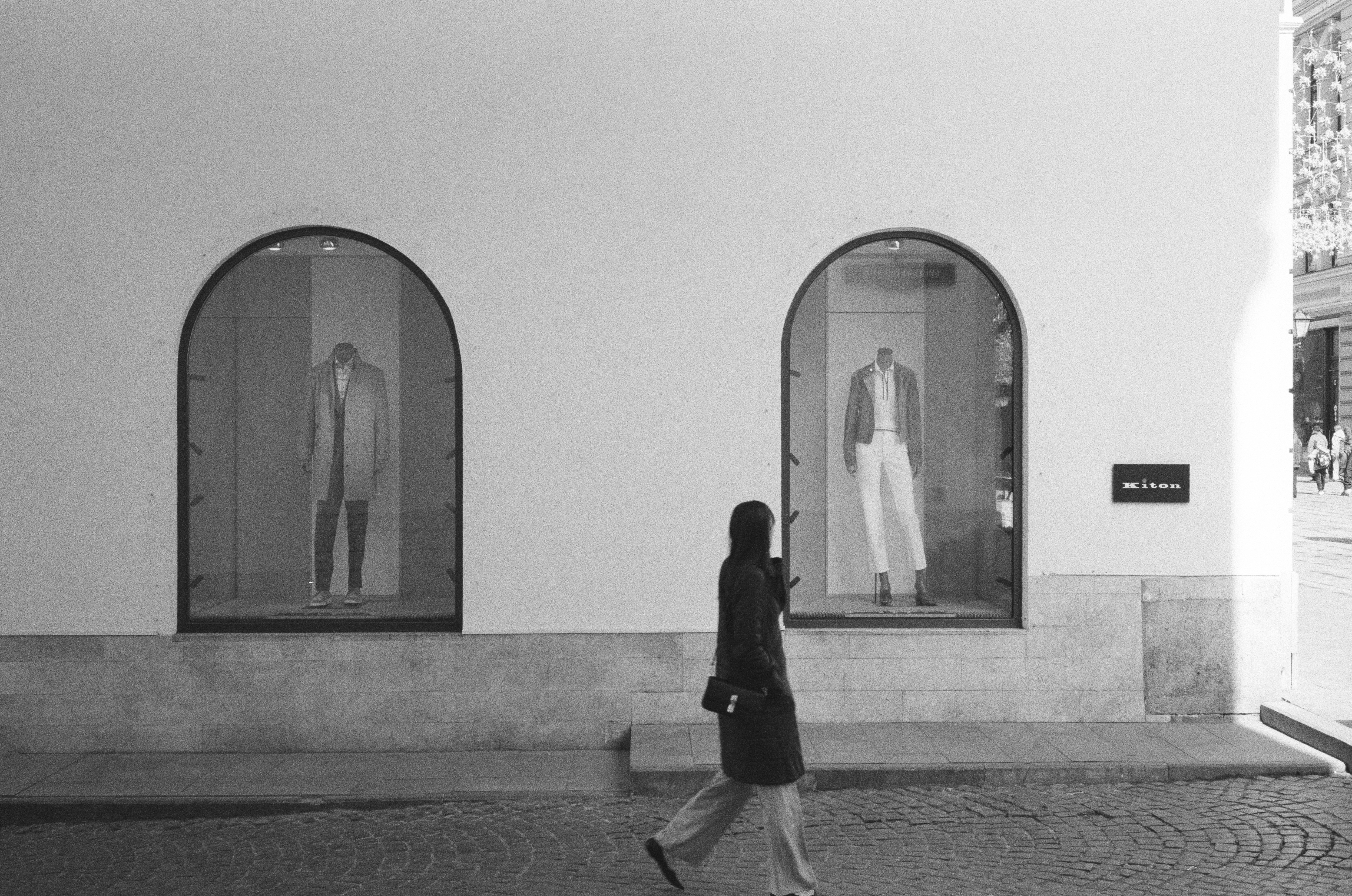A person walks past two shop windows with clothing displays