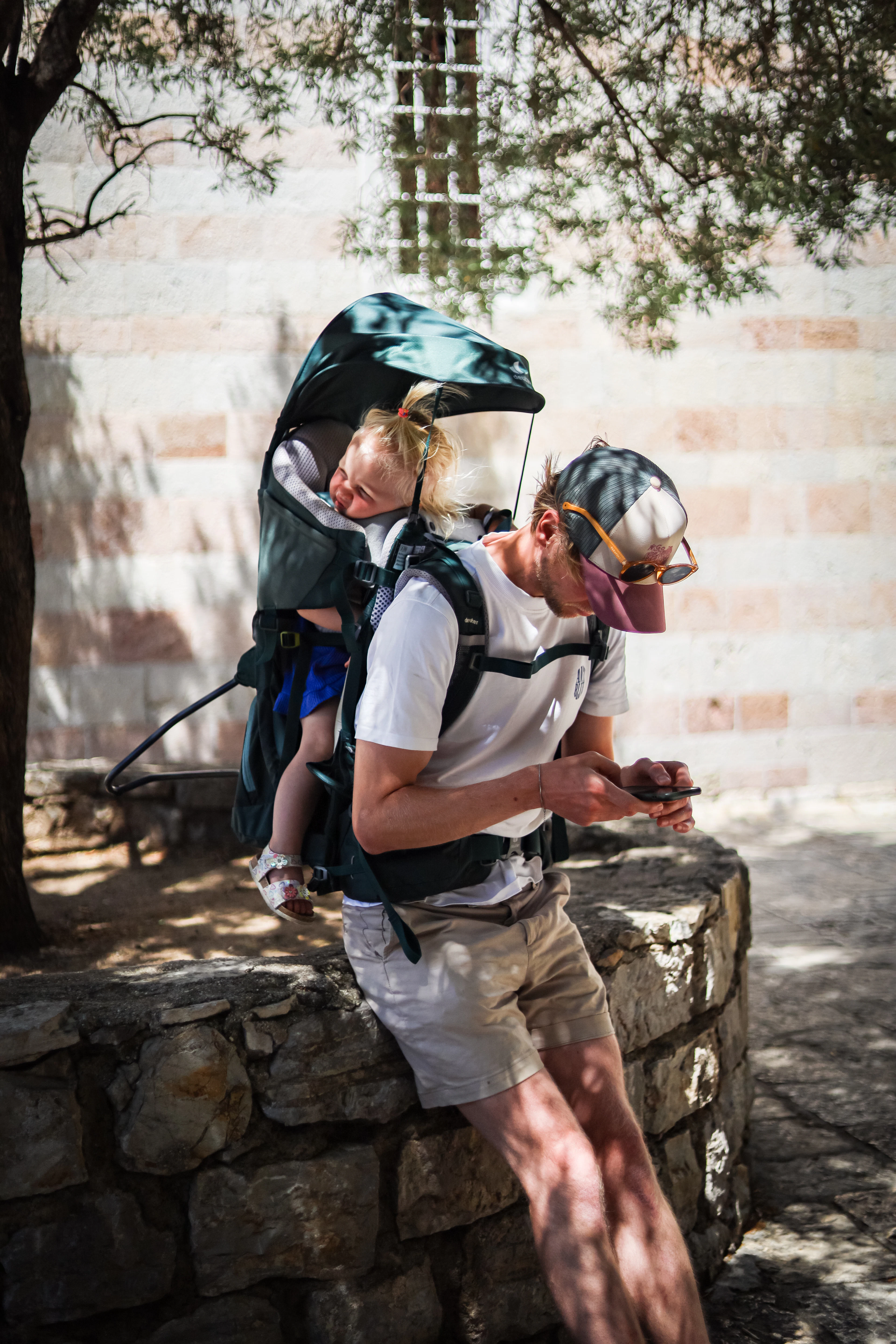 A parent wearing a framed kid carrier backpack outdoors