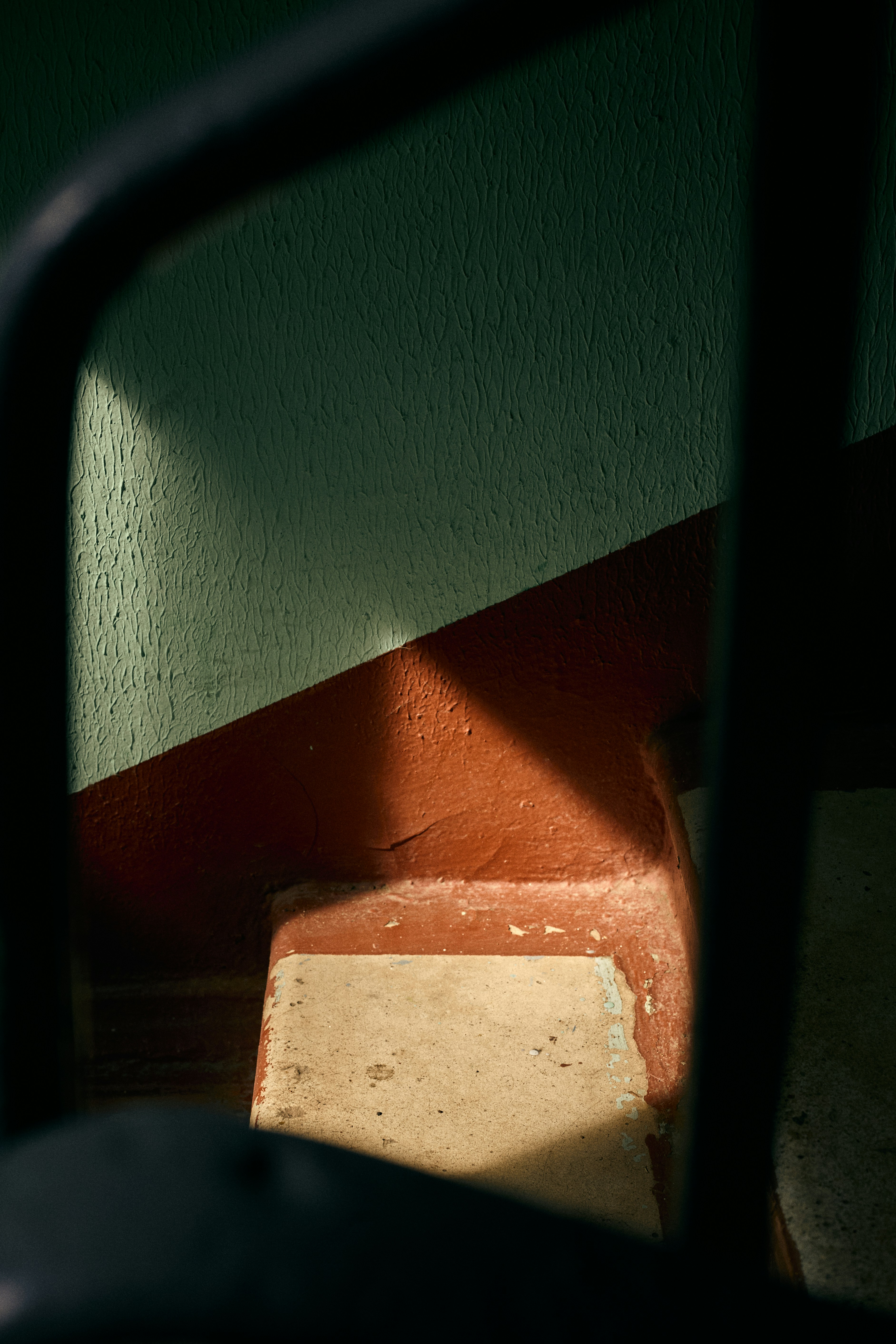 Sunlight casts shadows on a green and red staircase.