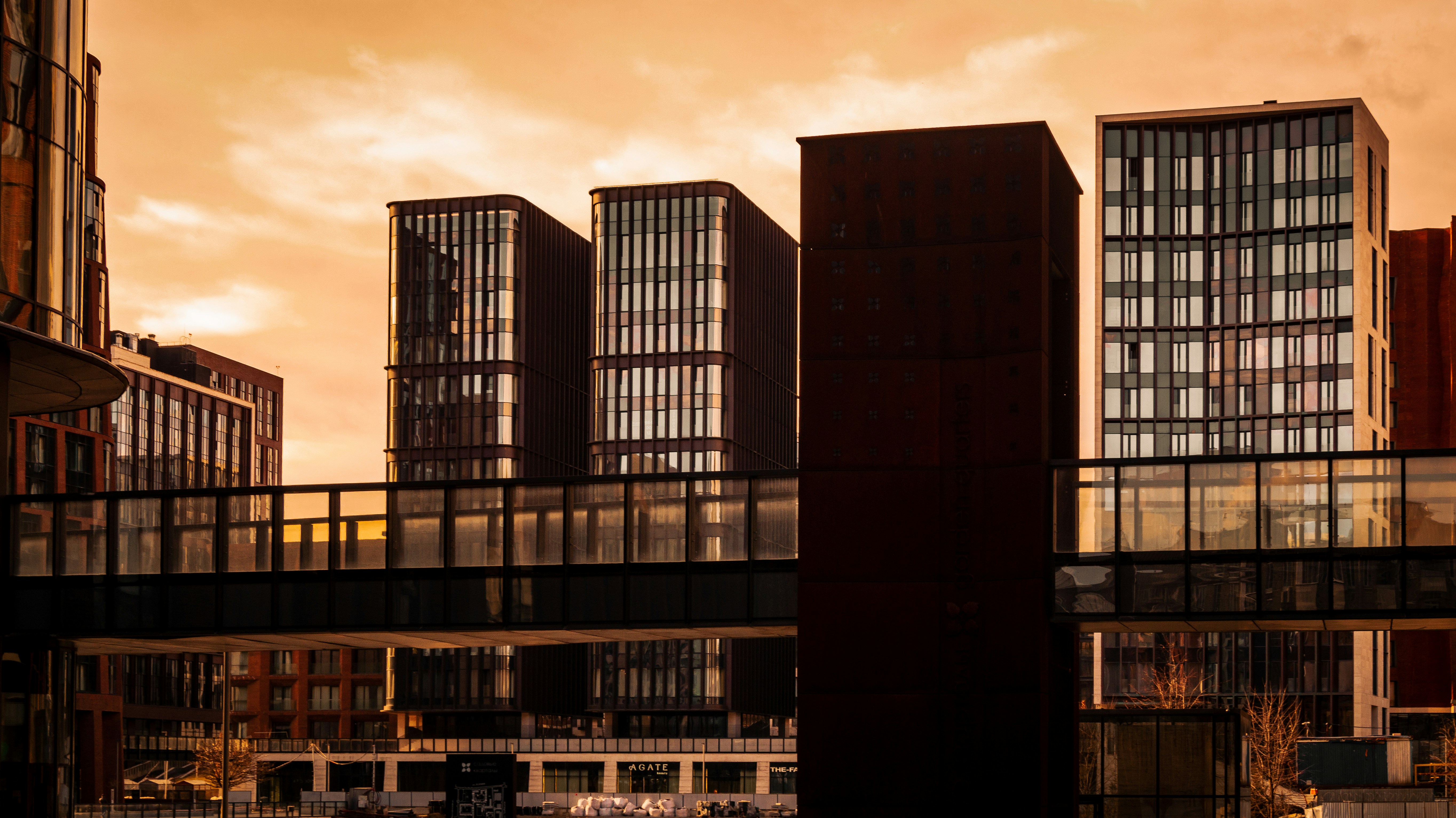 Modern buildings with connecting walkways against an orange sky.