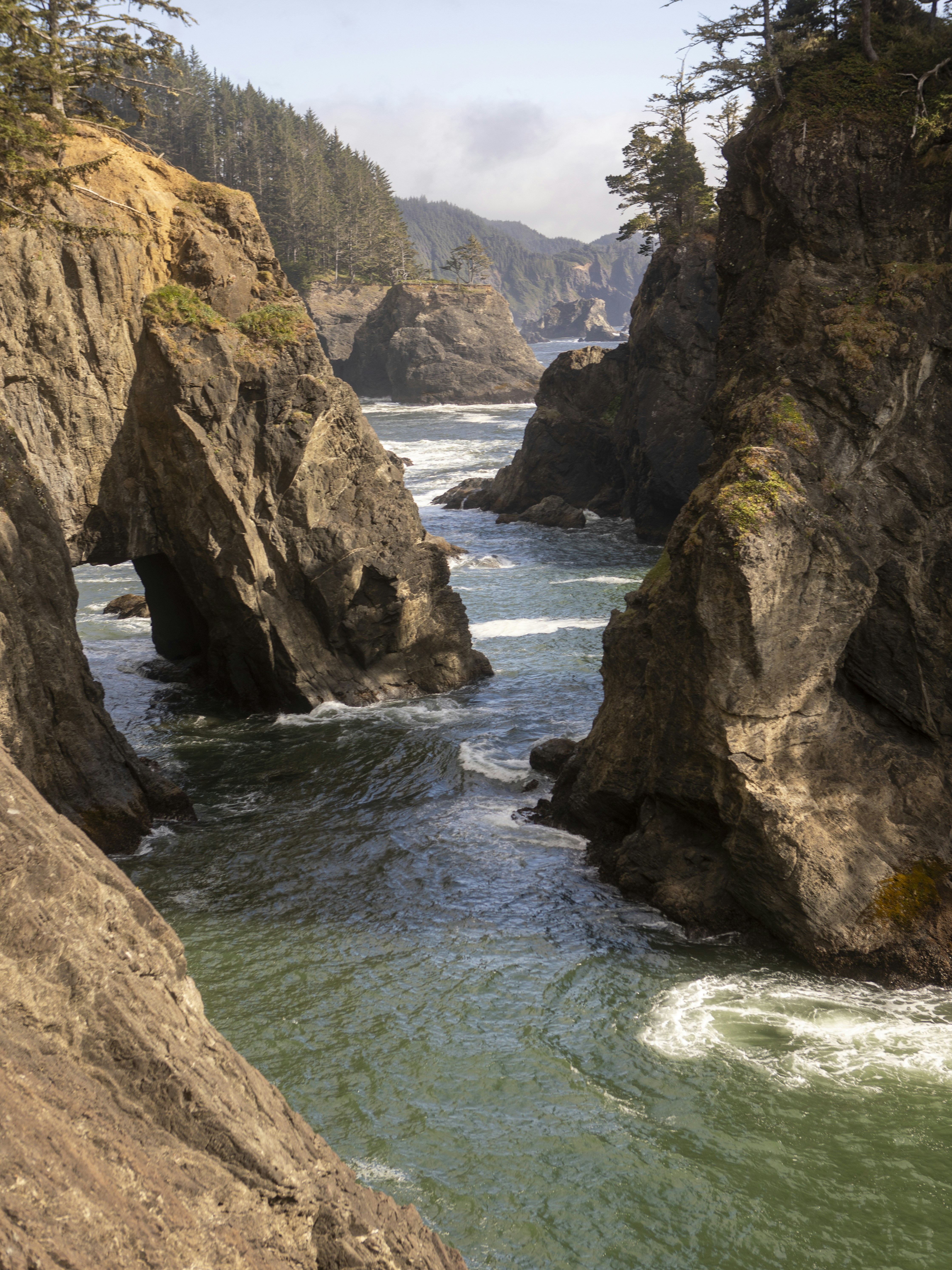Rugged coastline with natural rock arch and ocean waves