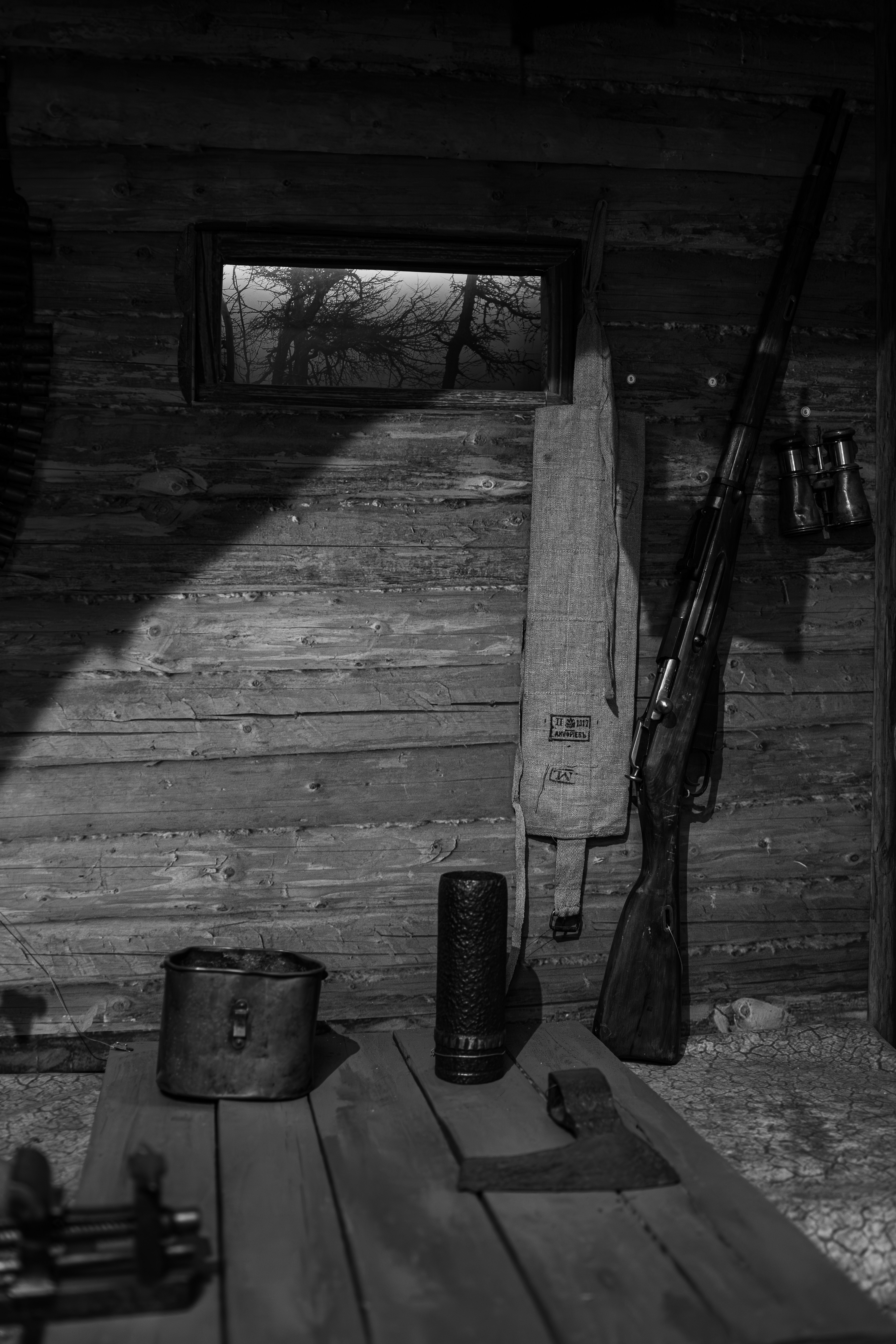Rustic wooden interior with rifle, axe, and window view.