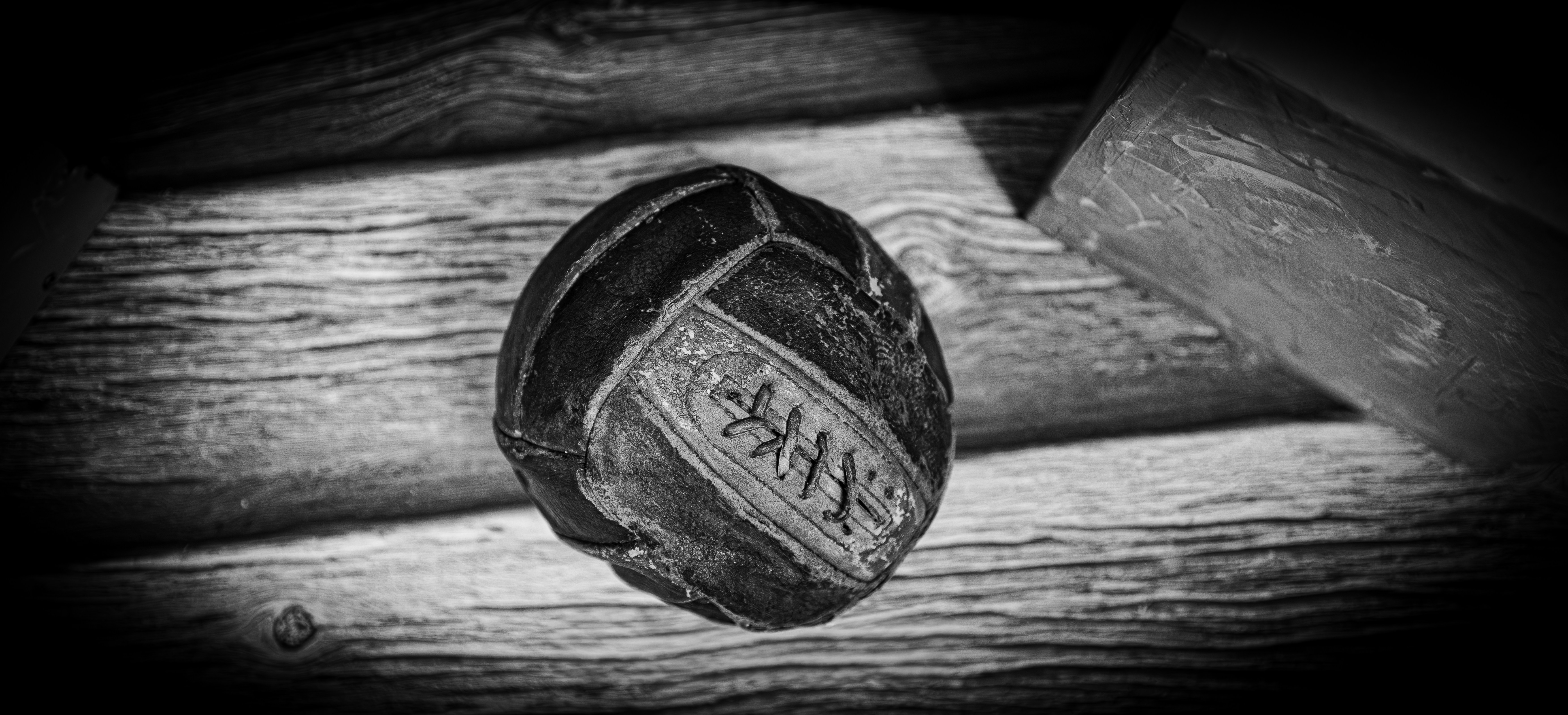 Old, worn volleyball with markings on rustic wooden surface.