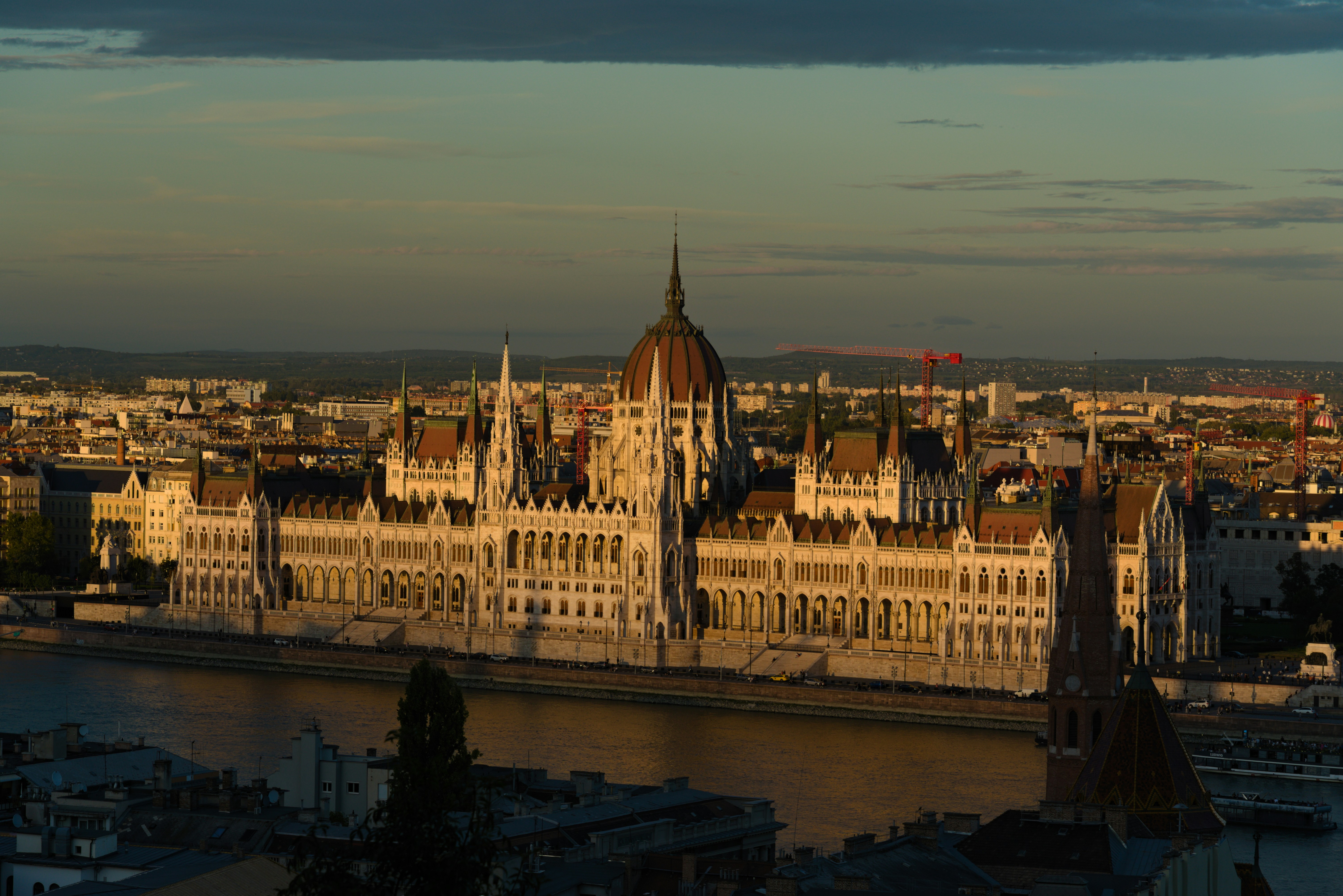 Hungarian parliament building at sunset along the danube river.