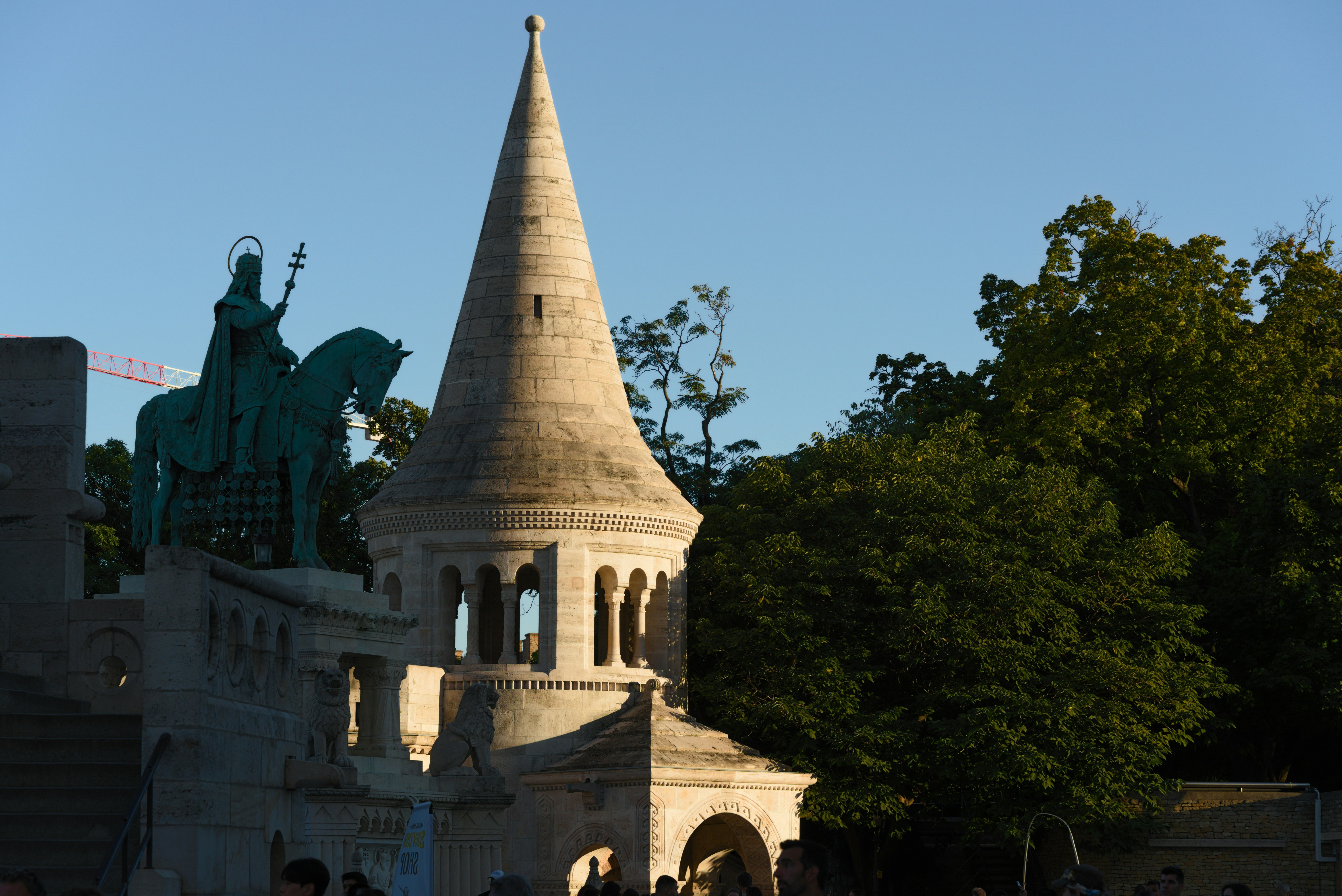 Stone tower and equestrian statue against blue sky.