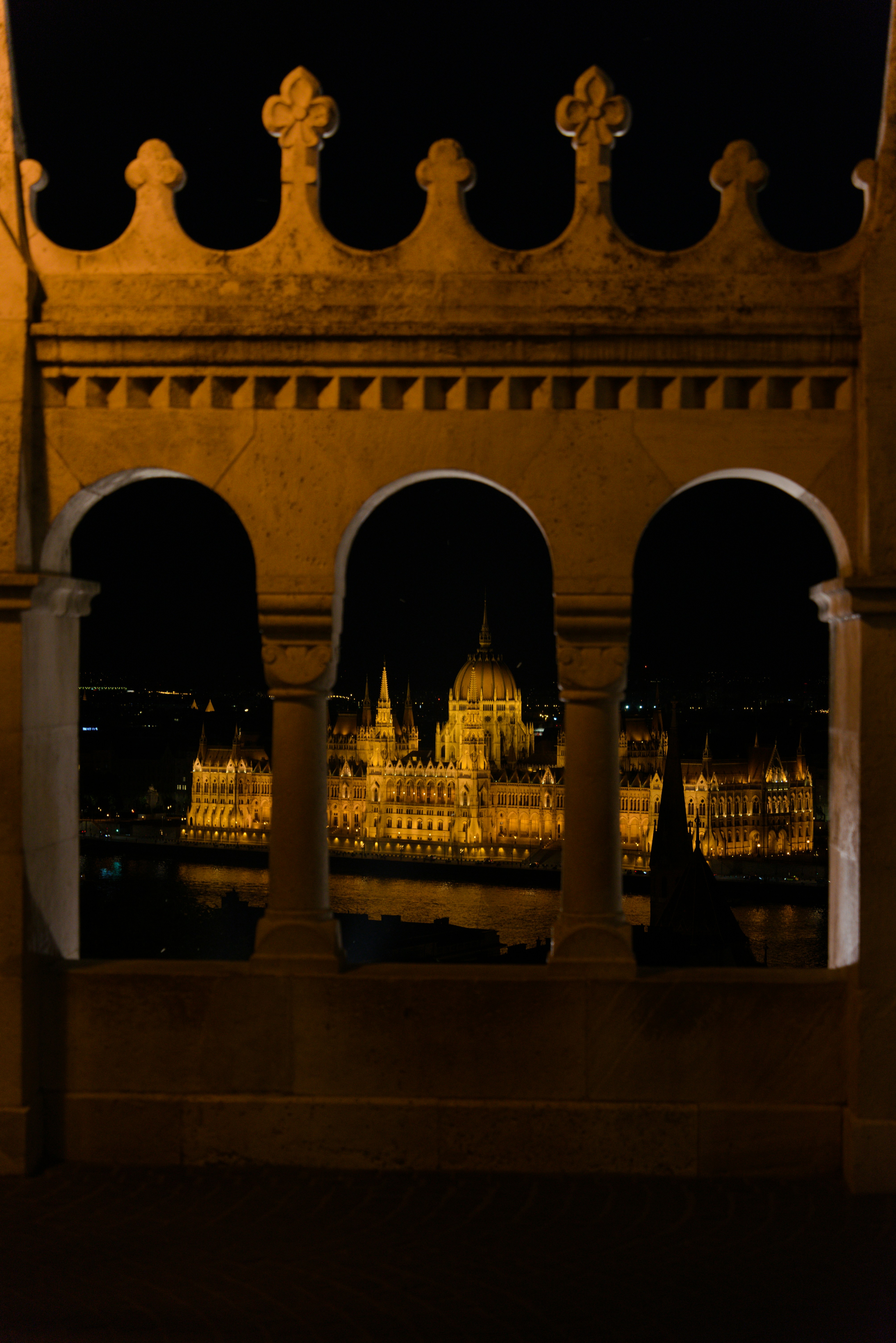 A grand building illuminated at night, viewed through stone arches.