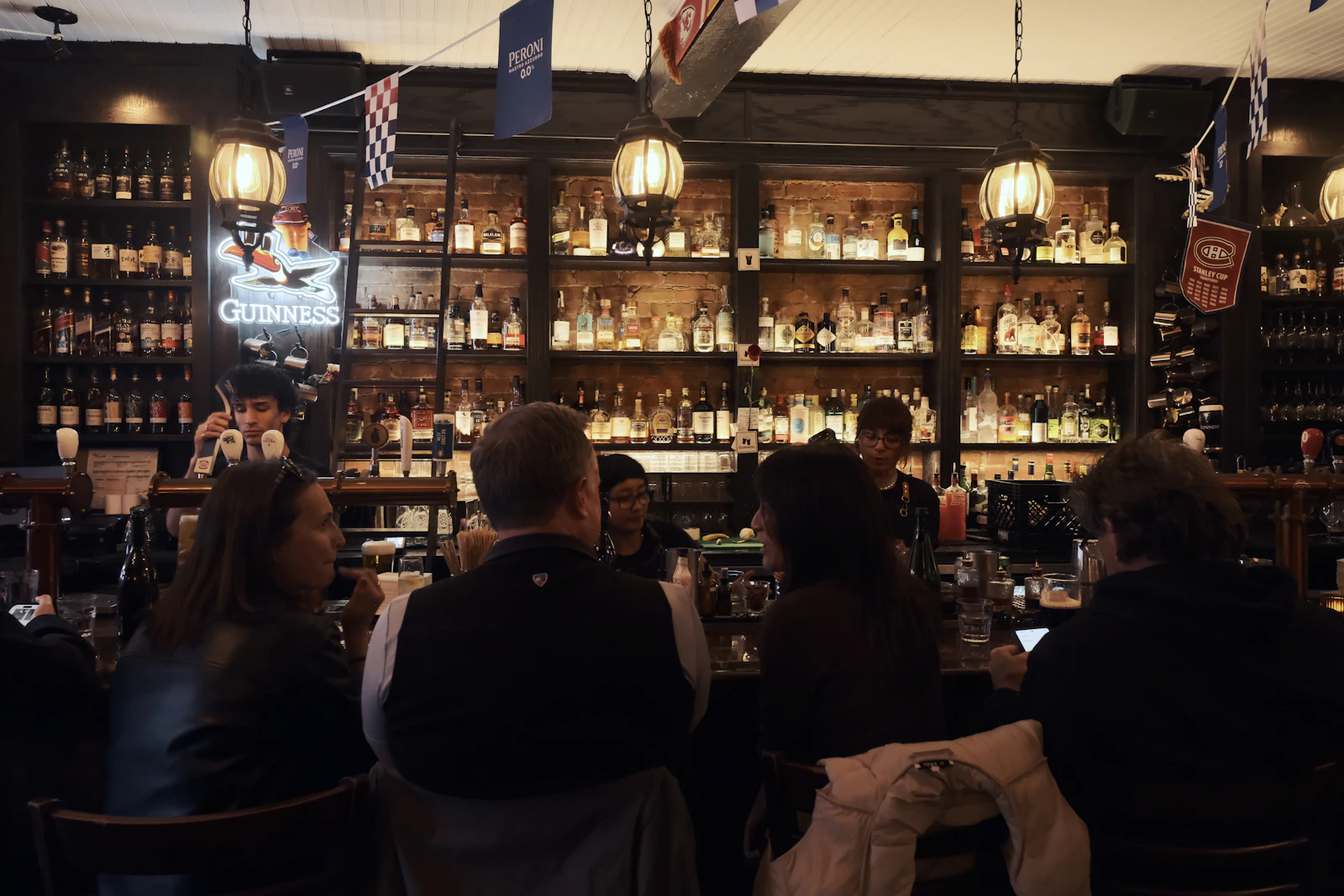 Two people talking over drinks at a dimly lit bar