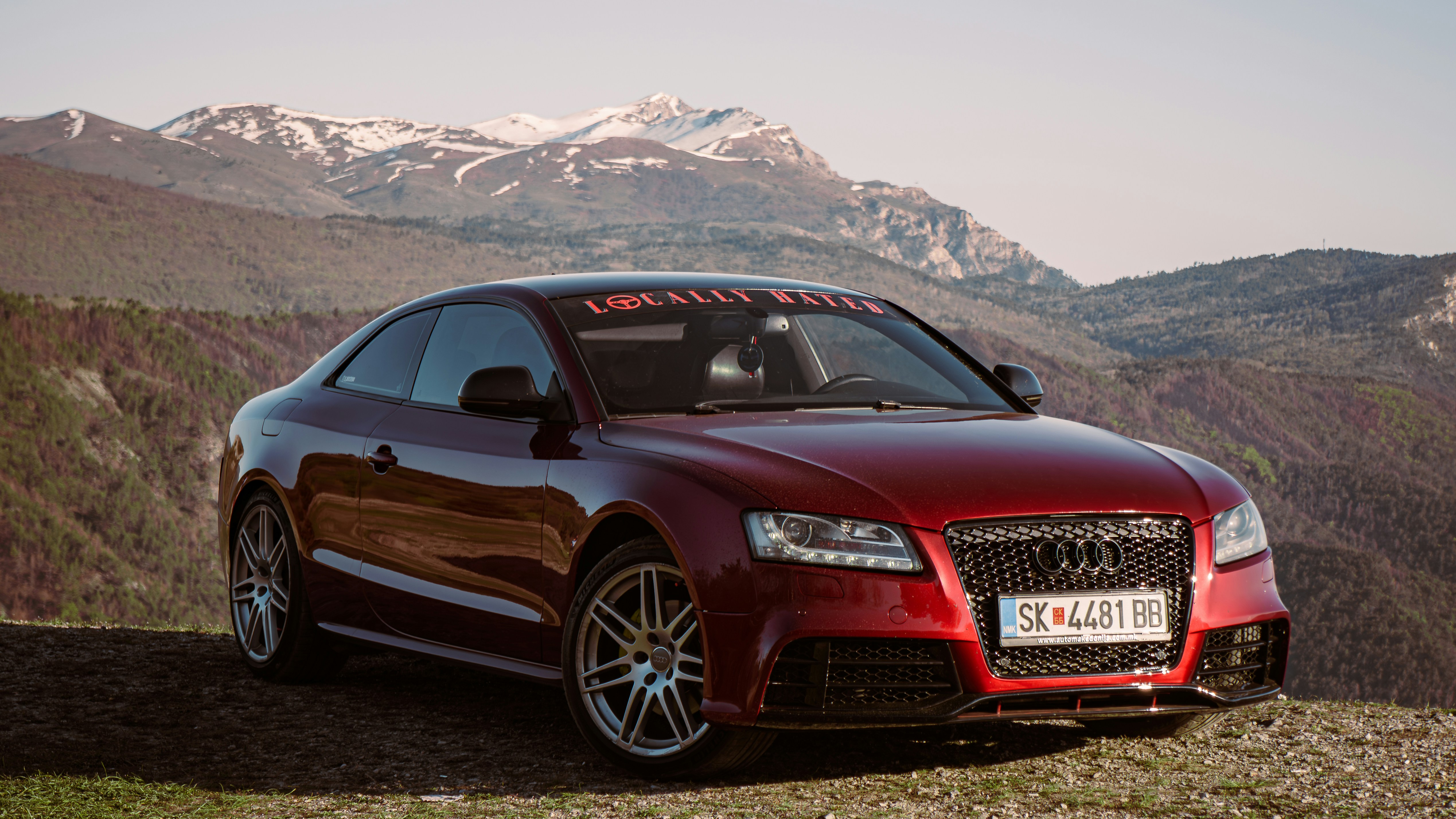 A red audi car parked outdoors with mountains in background