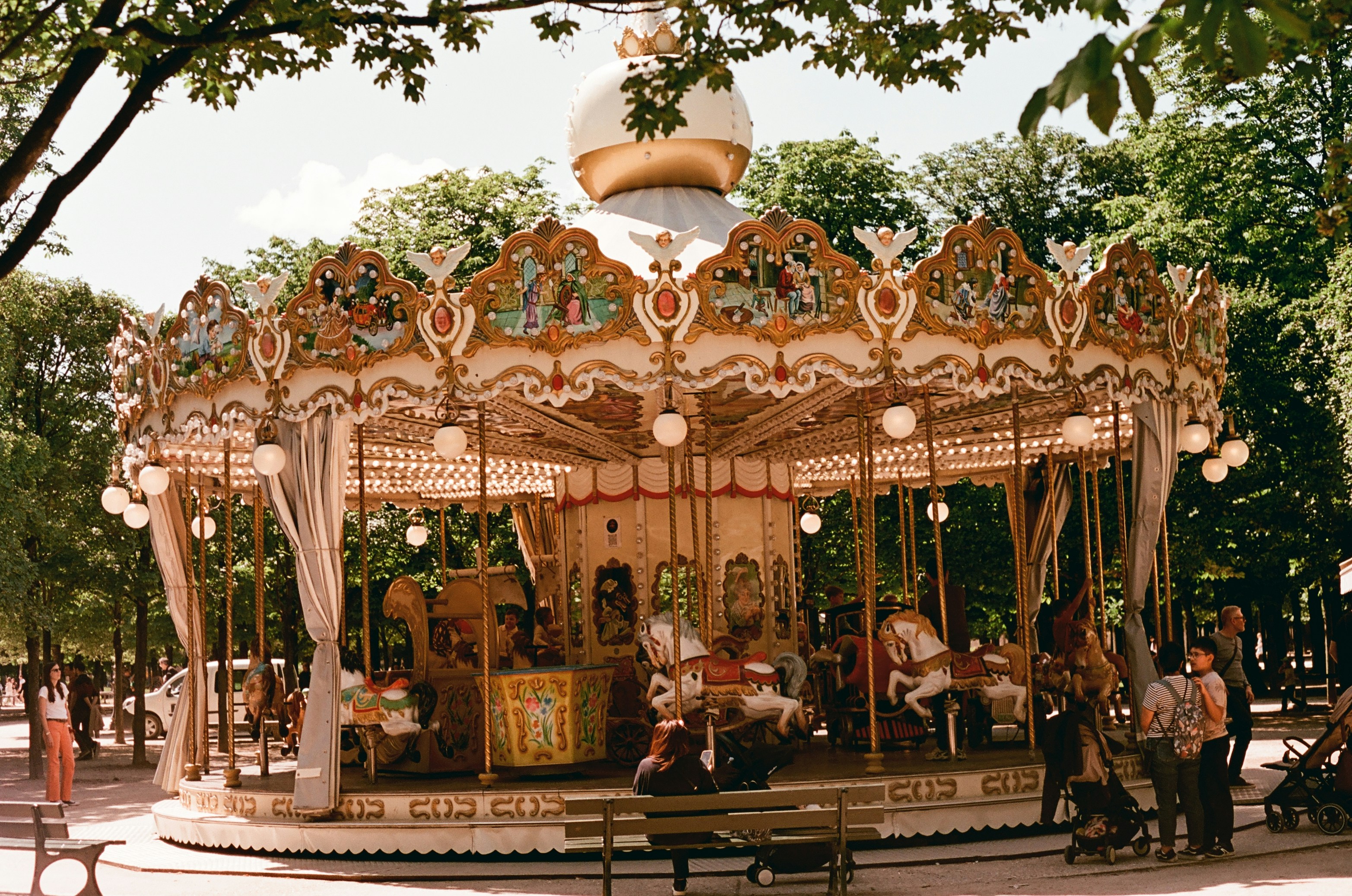 A beautiful vintage carousel in a park with green trees.