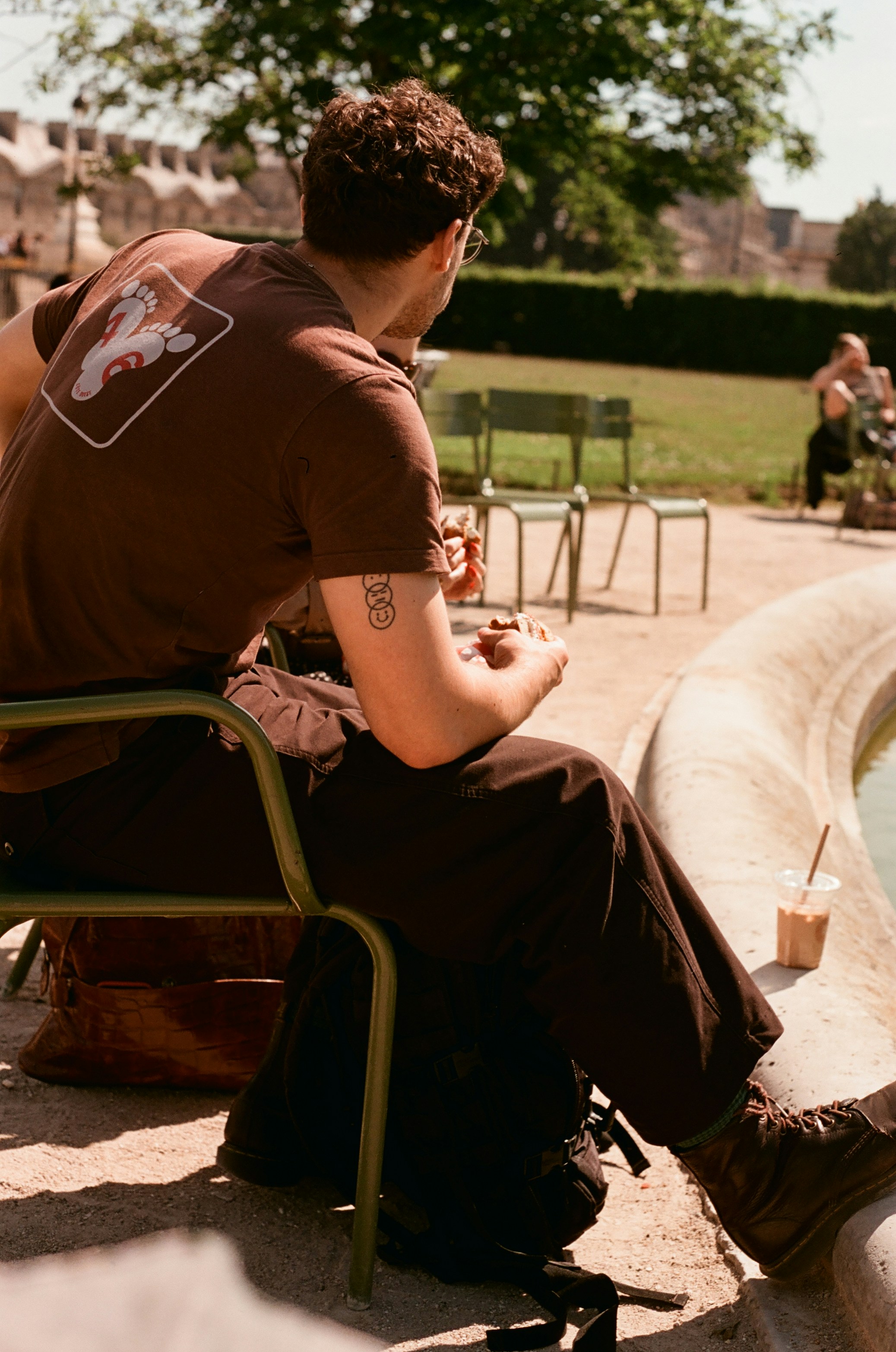 A man sitting outdoors on a chair, enjoying a drink.
