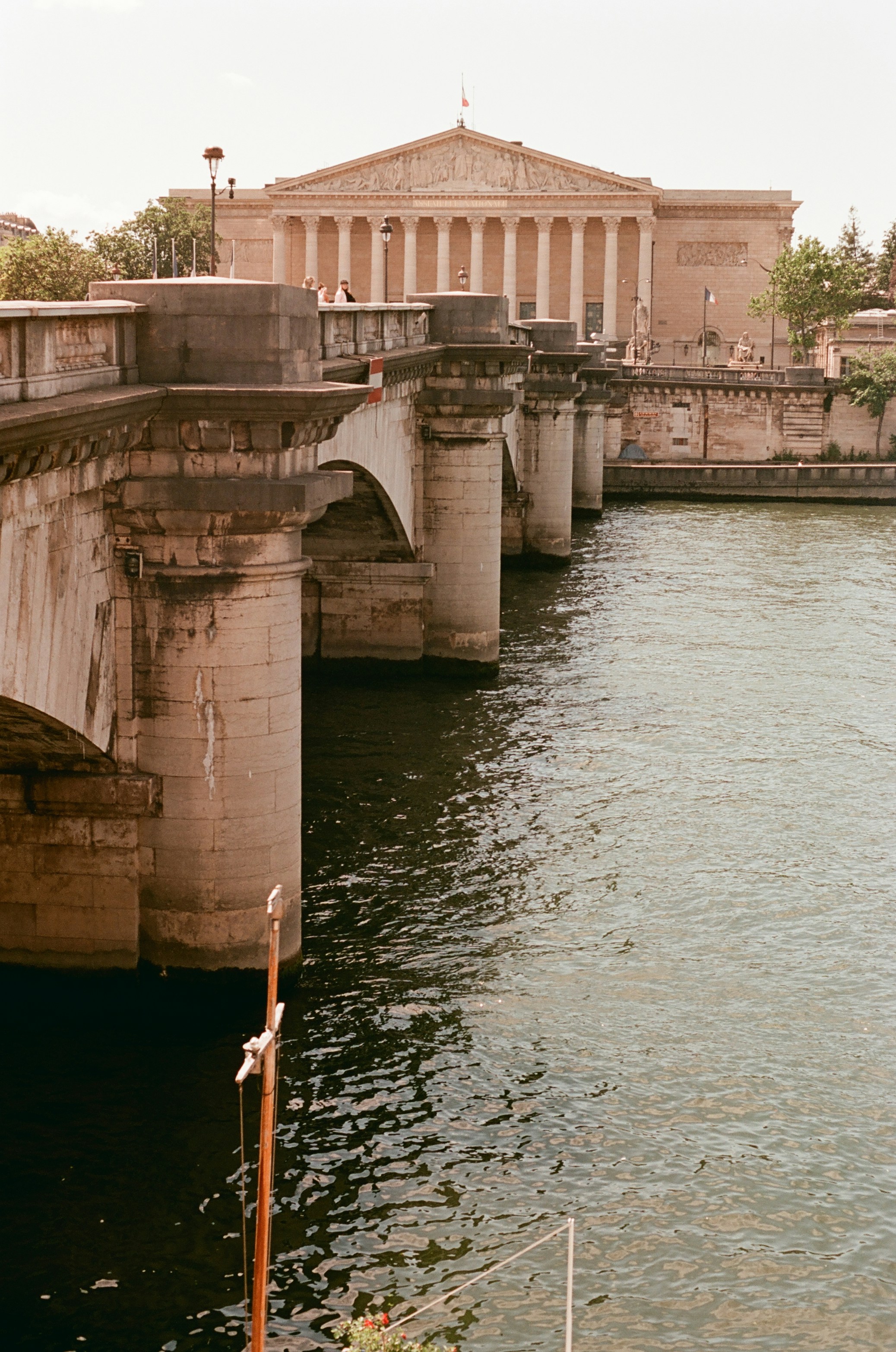 Stone bridge spanning a river with a classical building.