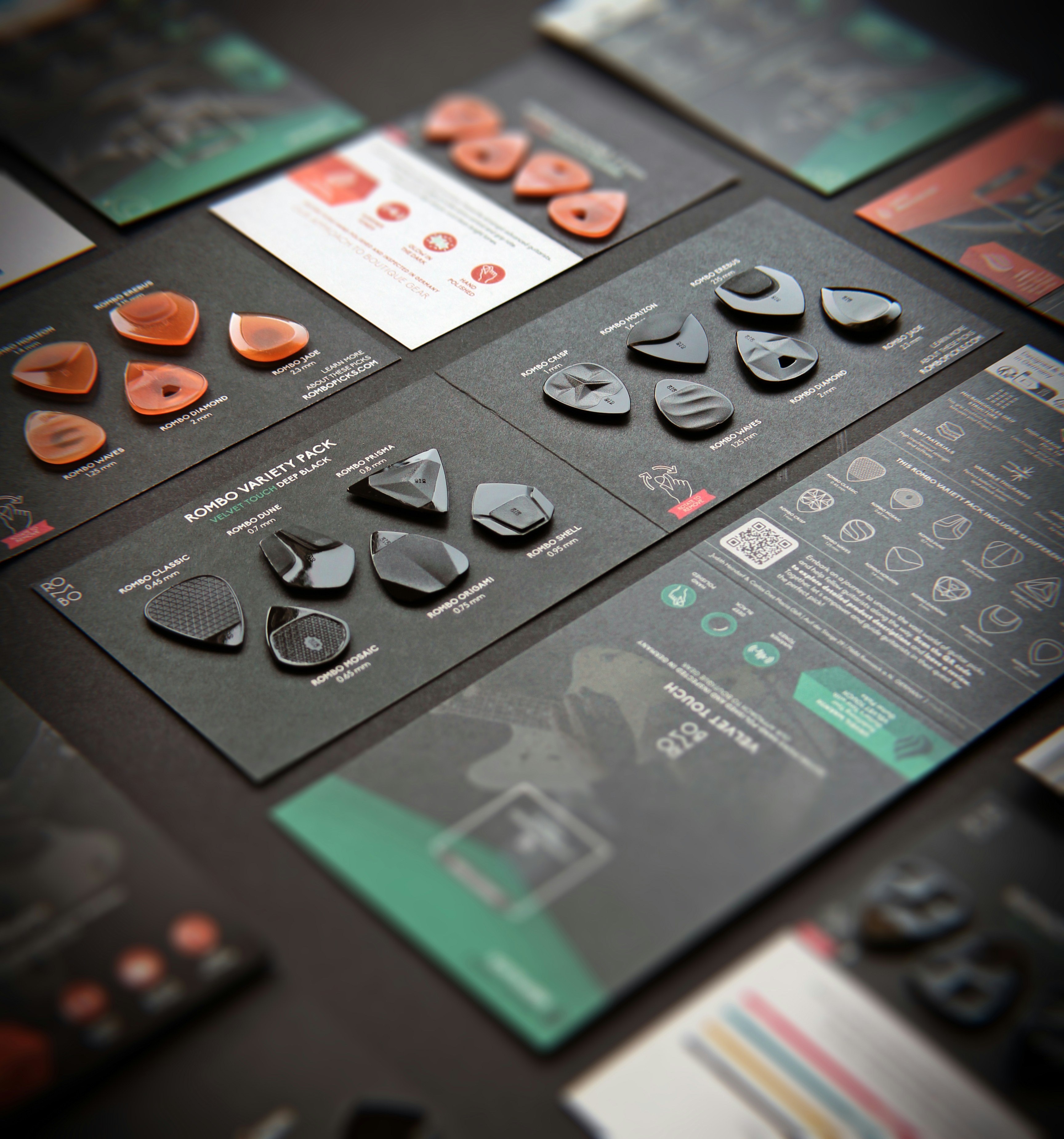 Various guitar picks displayed on black cards with information.