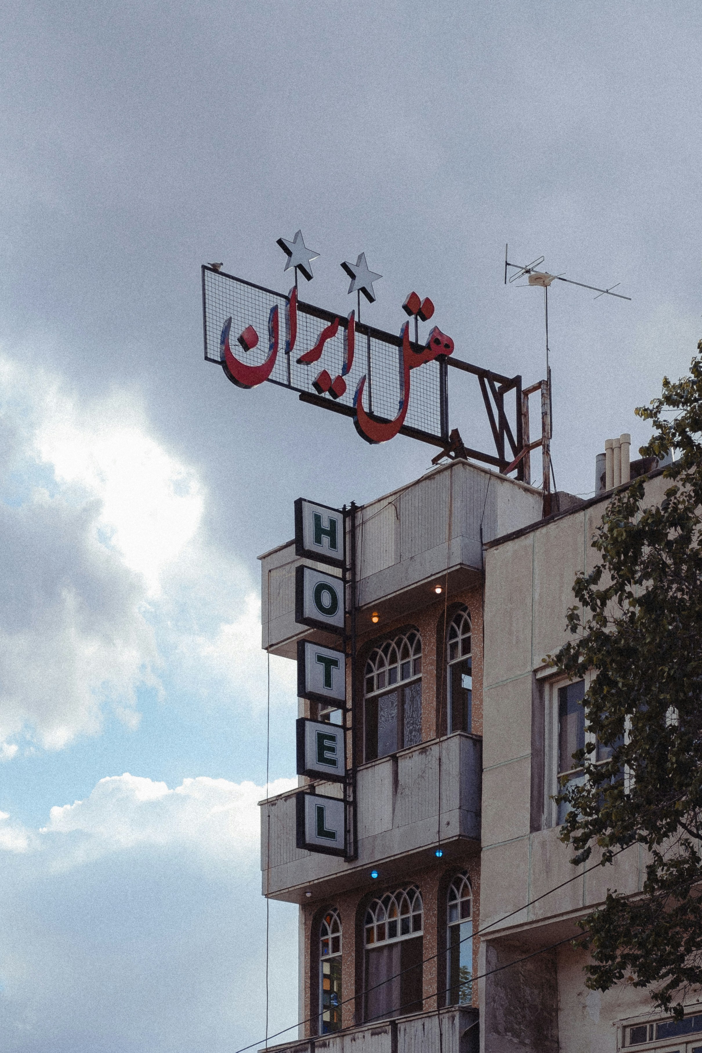 Tanda hotel vintage dengan aksara Persia di sebuah bangunan.