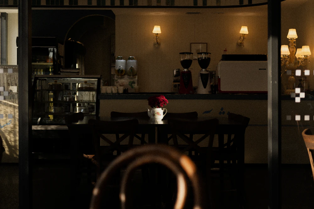 A cozy bakery cafe corner, with a pastry case, coffee, and fresh flowers.