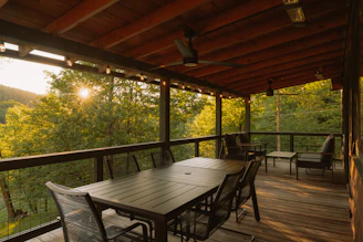 Rustic outdoor patio with dining set and sunlit forest view.