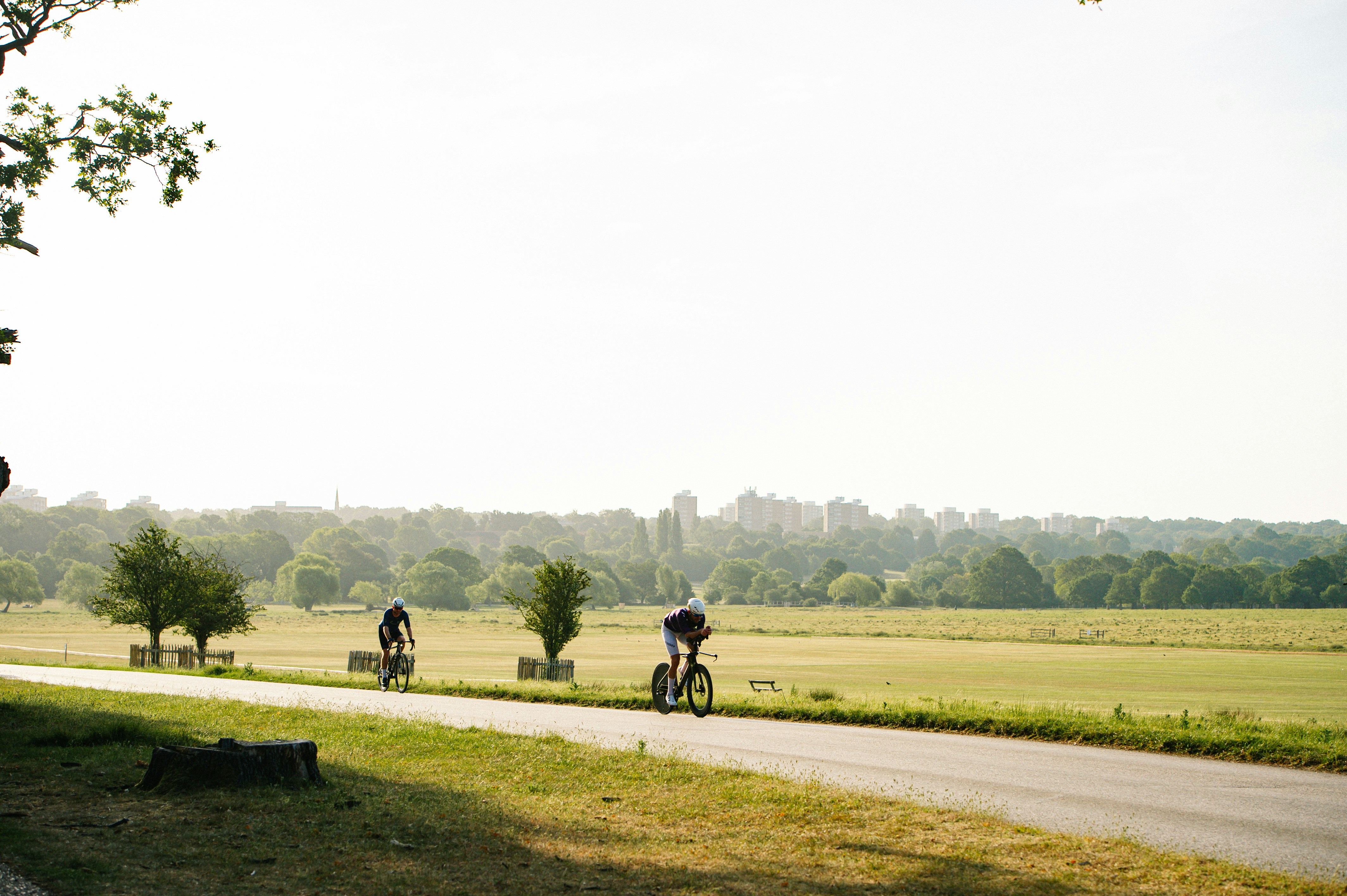Ciclistas em uma estrada com campos e horizonte distante da cidade.