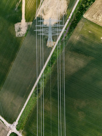 Aerial view of power line pylons over green rural fields