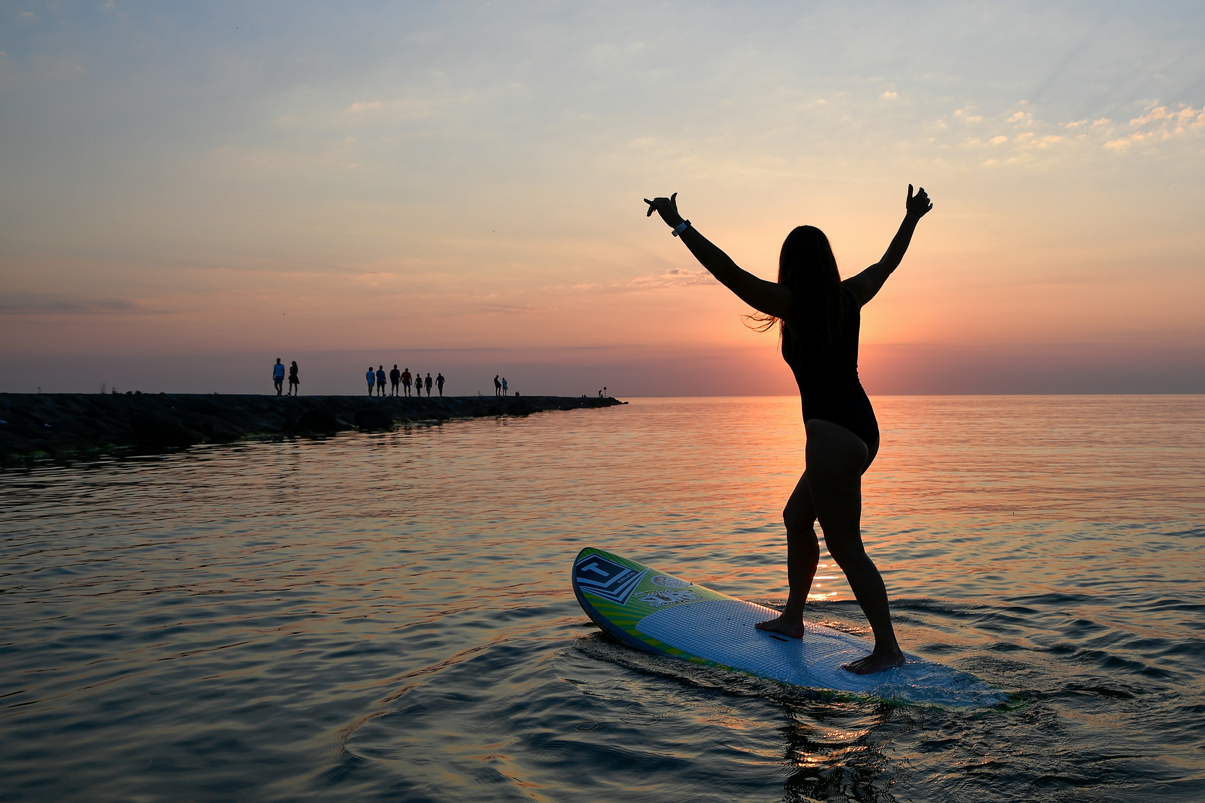 Silhouette of a woman on a surfboard at sunset