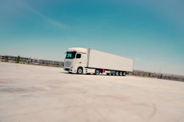 A white semi-truck parked on concrete under a blue sky.