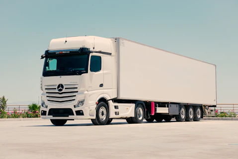 A white mercedes-benz semi-truck with a trailer parked outdoors