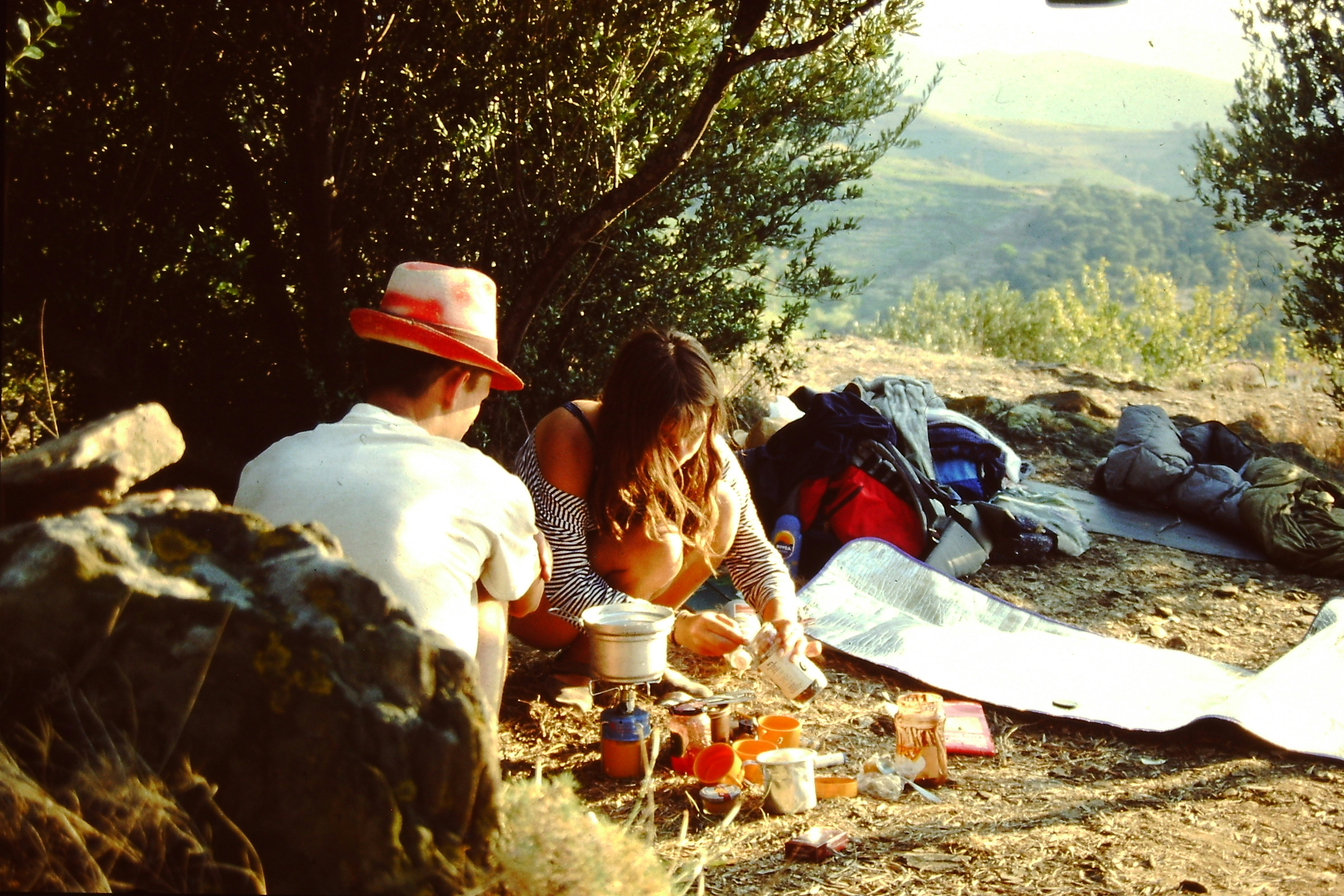 Two people camping, cooking a meal on a portable stove