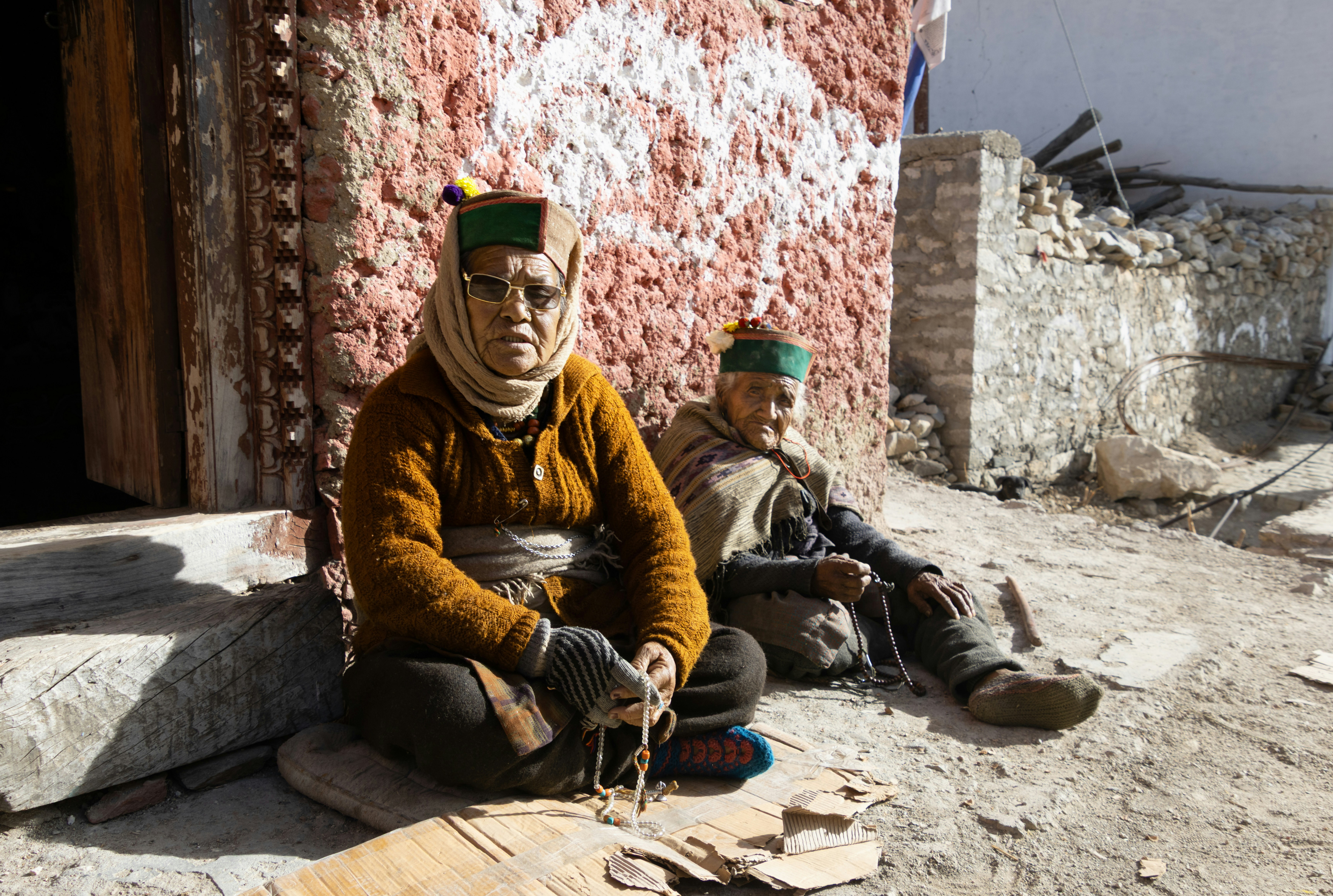 Des hommes et des femmes âgés s’assoient dehors en tenue traditionnelle.