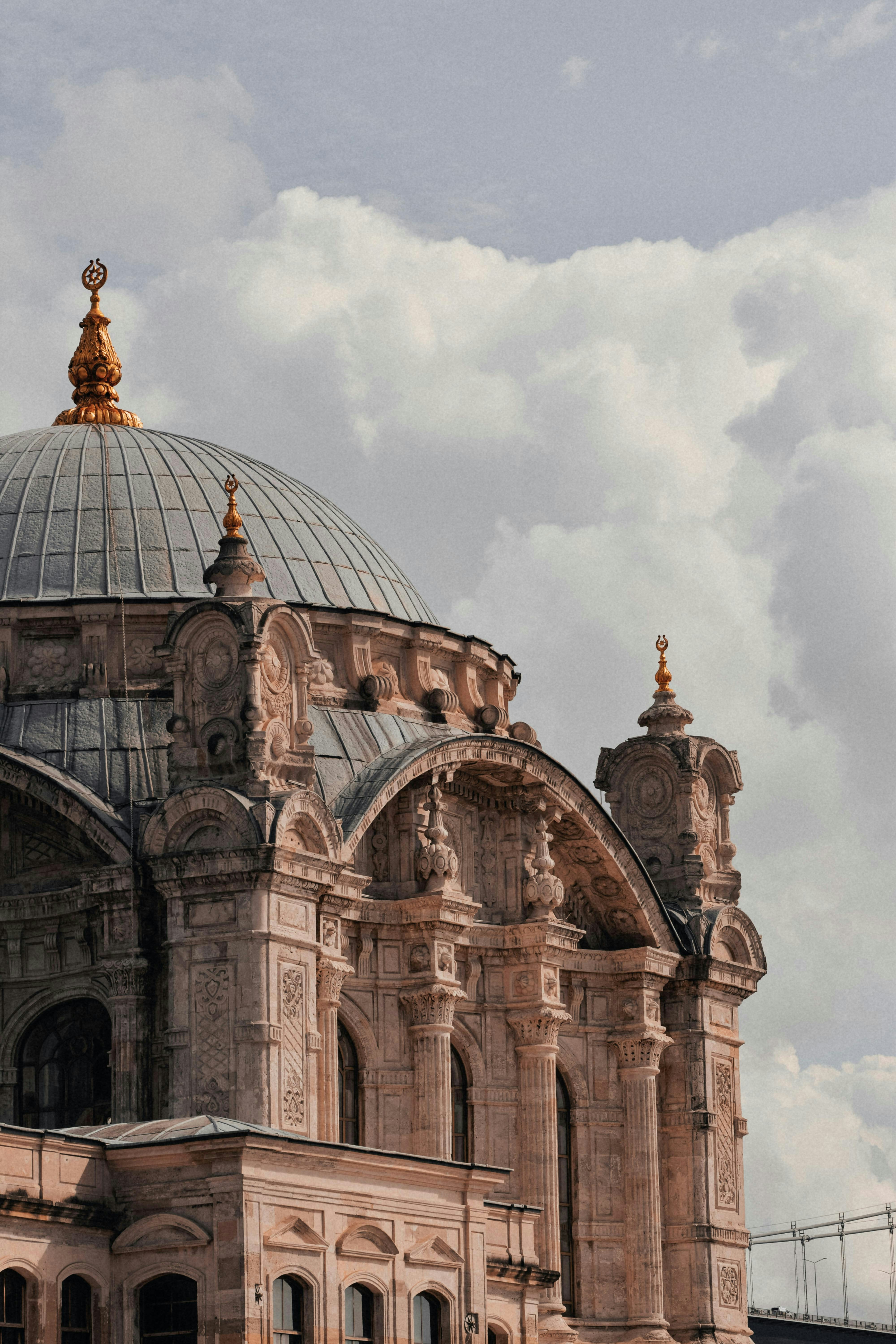 Ornate mosque dome and facade under a cloudy sky
