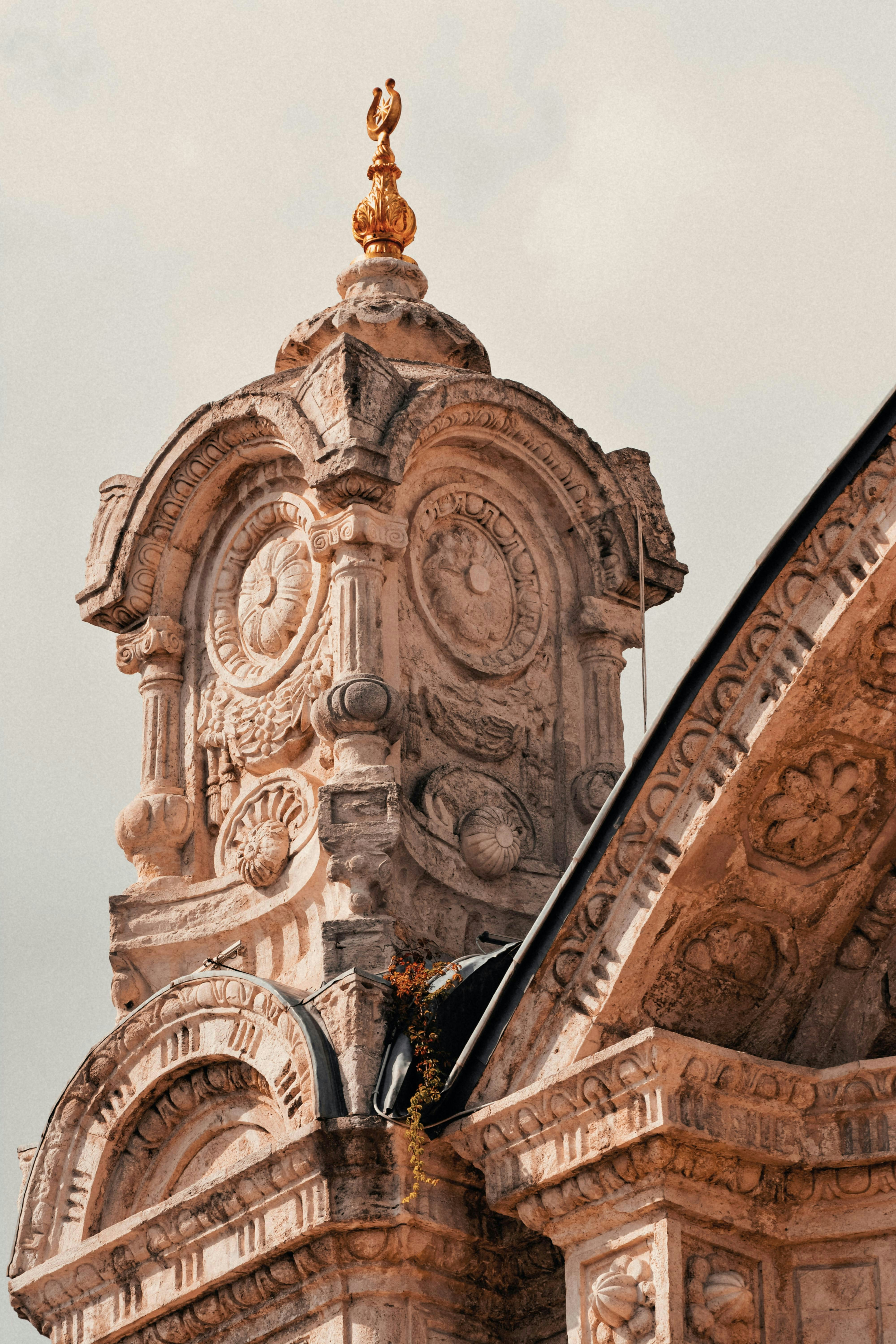 Ornate stone architecture with intricate carvings and a golden finial
