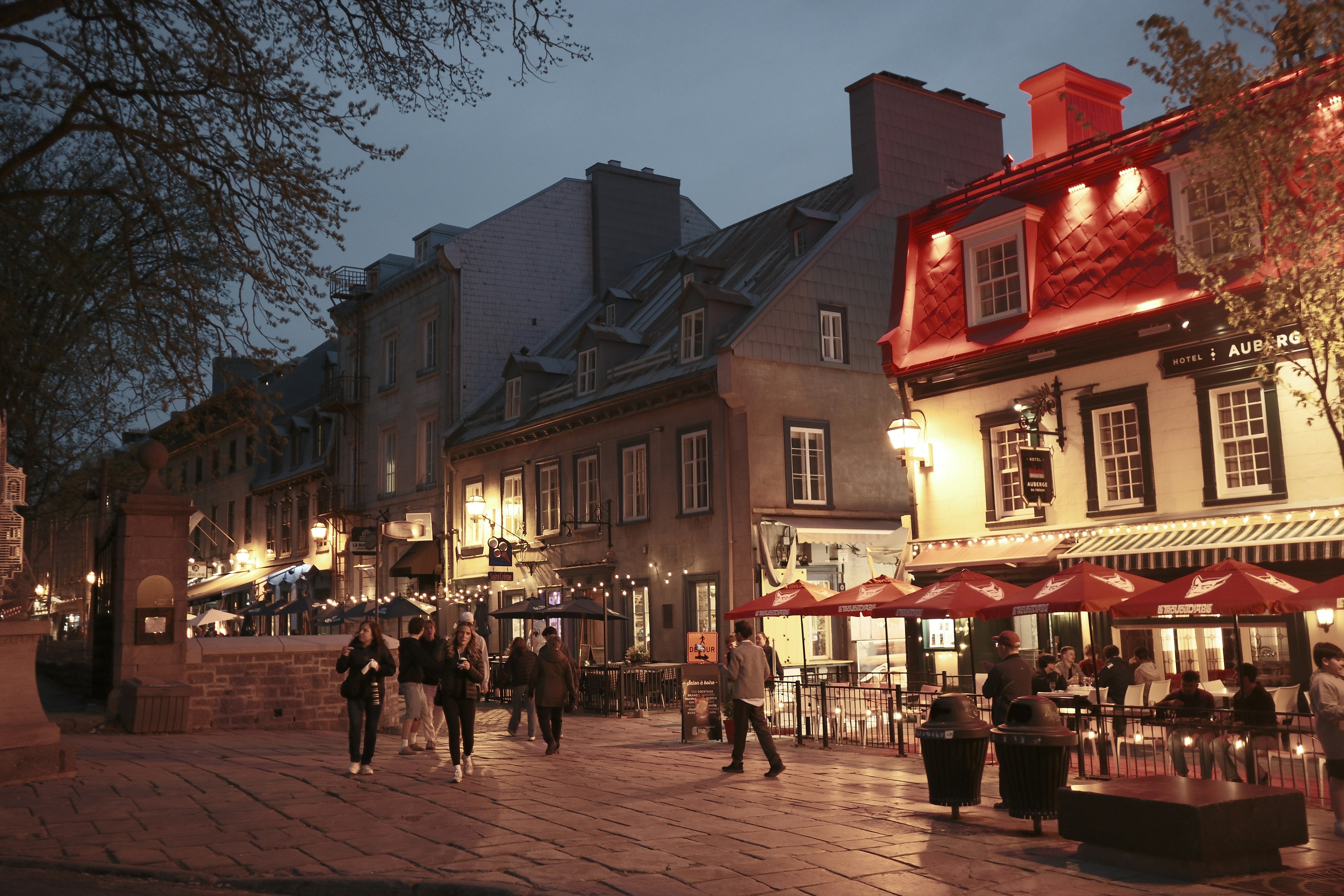 Historic street with people and illuminated buildings at dusk