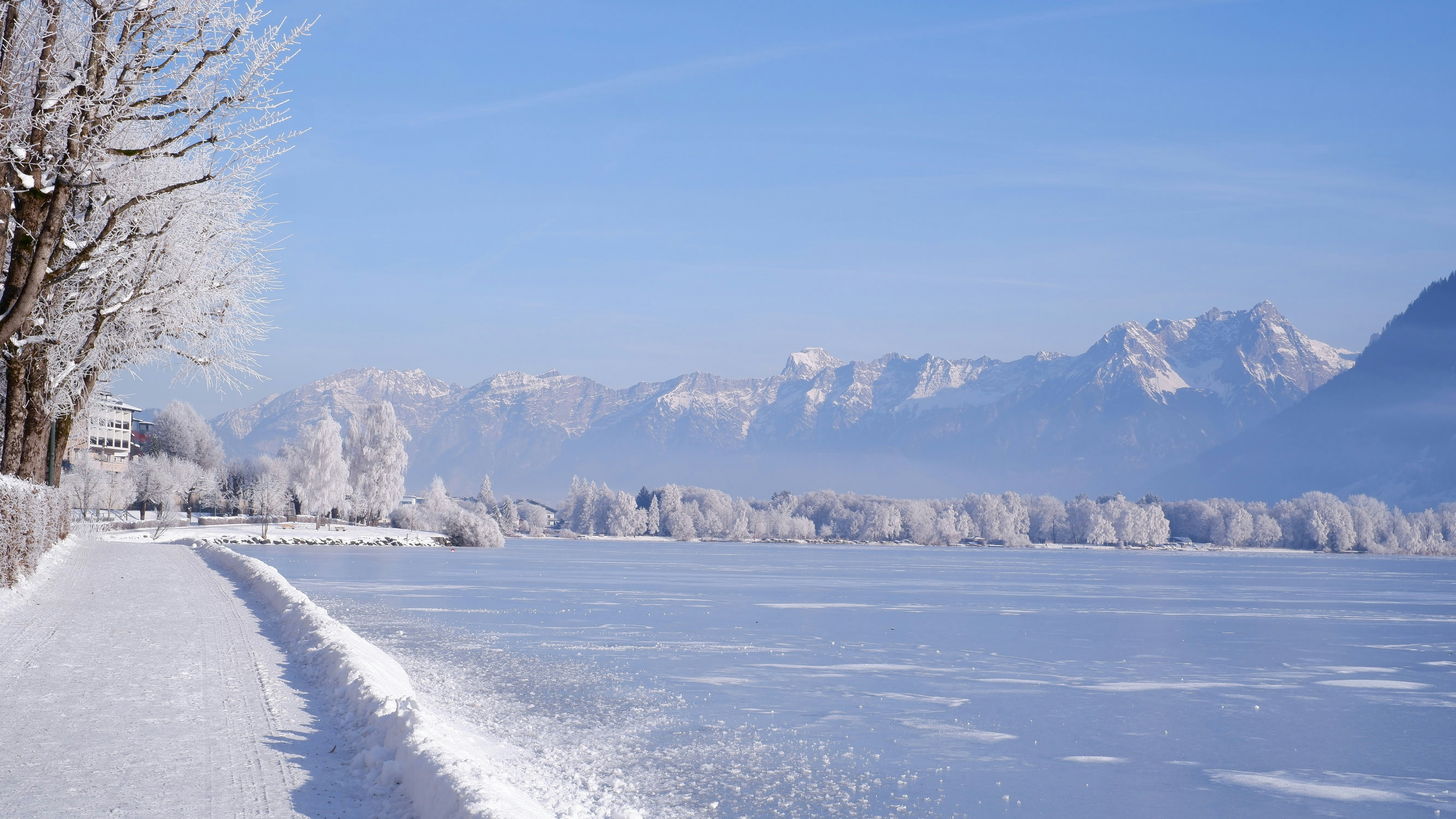 Serene winter landscape with frozen lake and snow-covered mountains ...