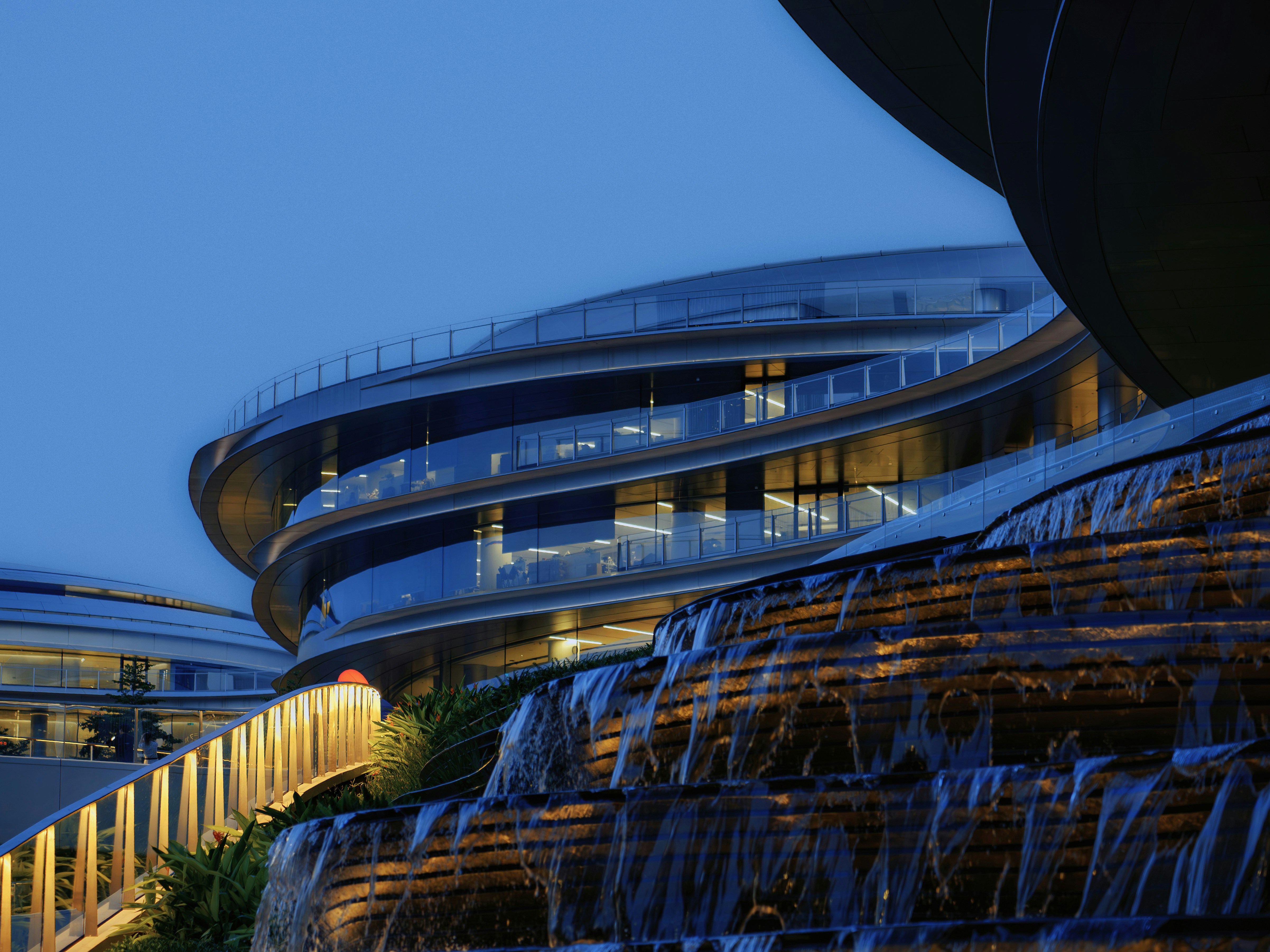 Modern building with curved architecture and tiered waterfall at night