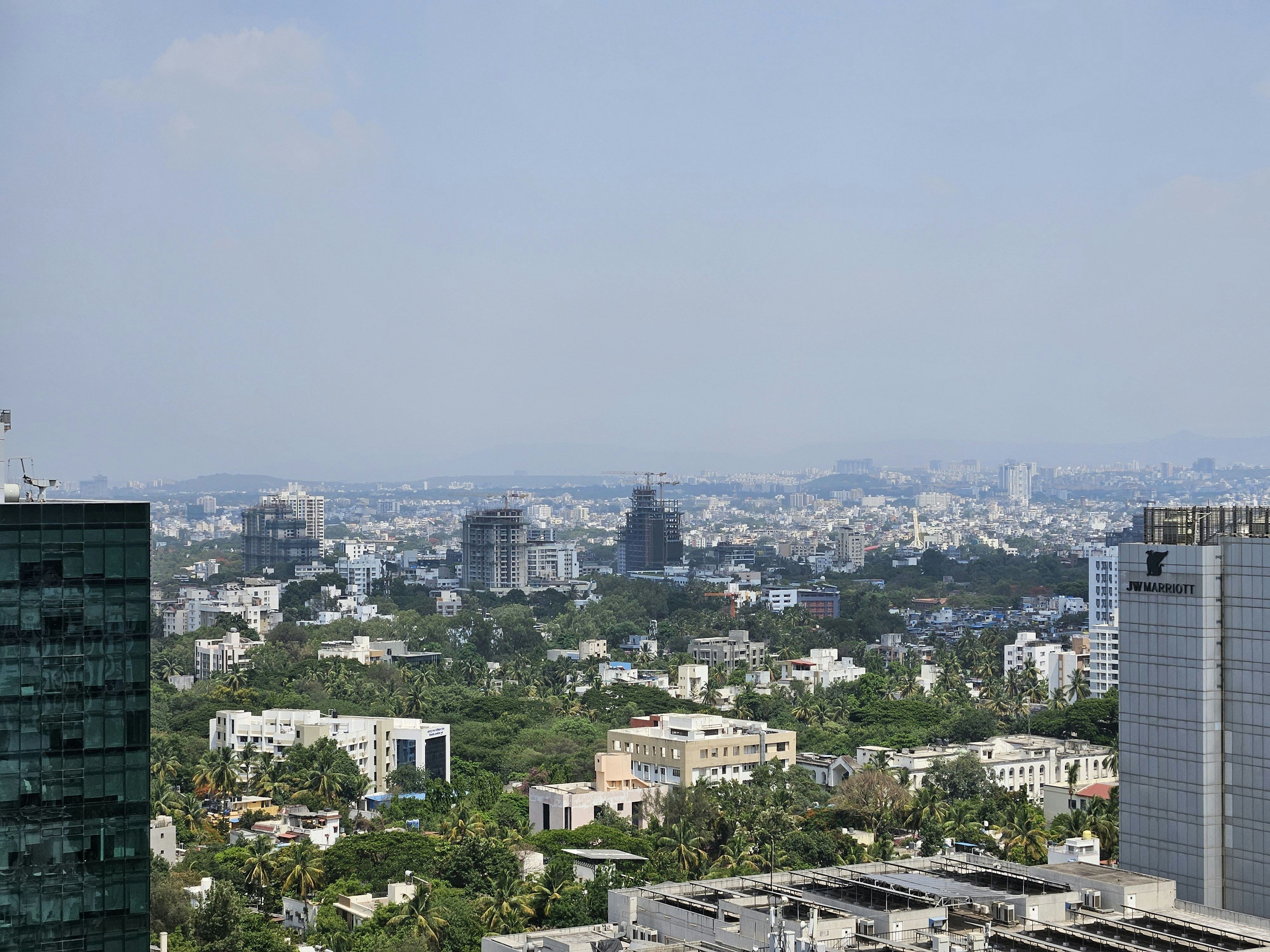 Paisagem urbana com edifícios em meio a abundante folhagem verde.