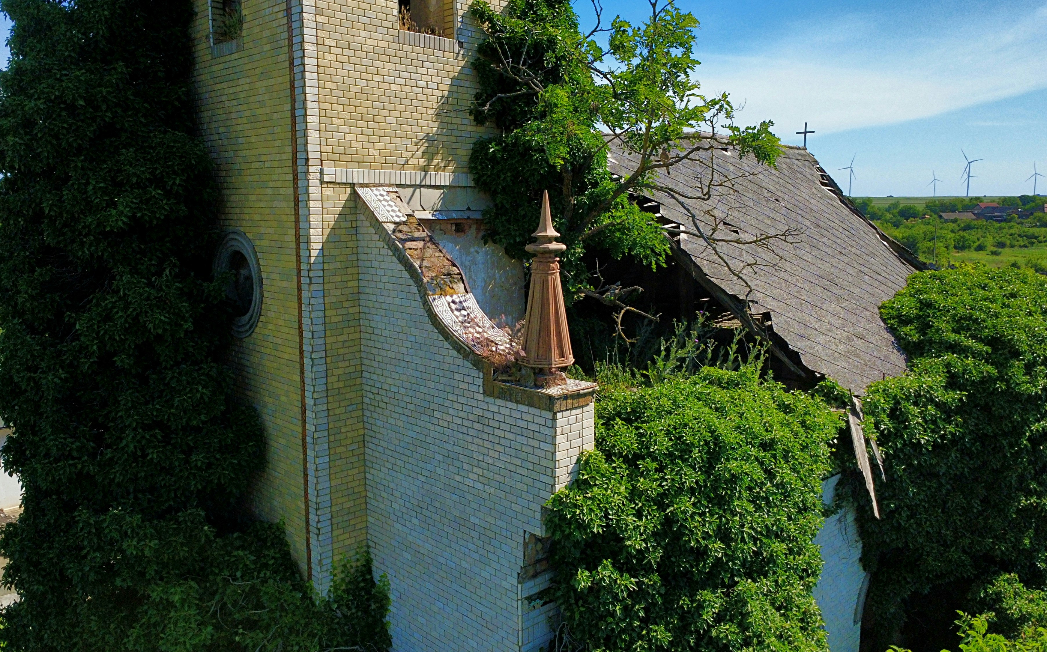 Decaying abandoned church building covered in lush green vegetation.
