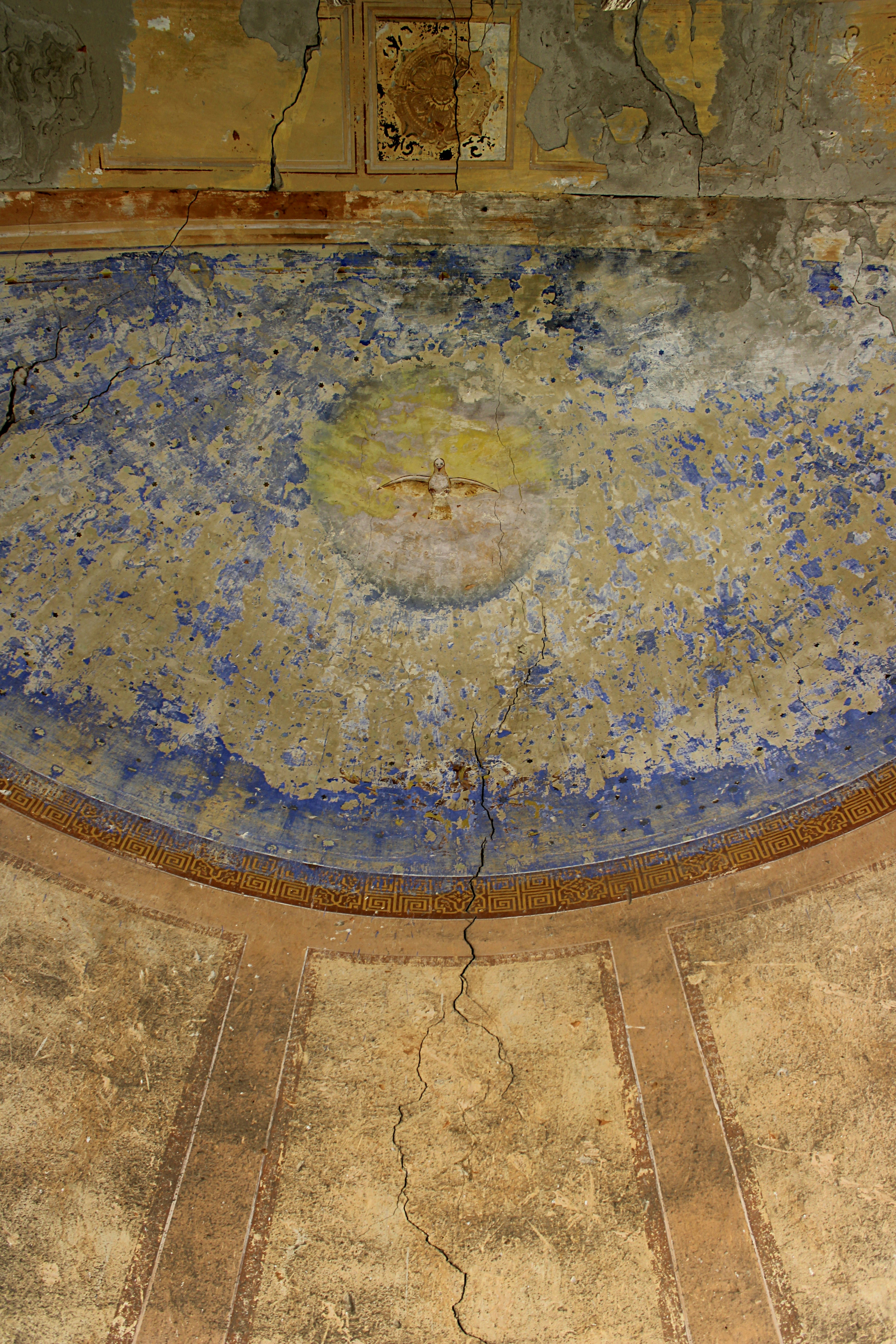 Faded fresco of a dove on an old, weathered ceiling.