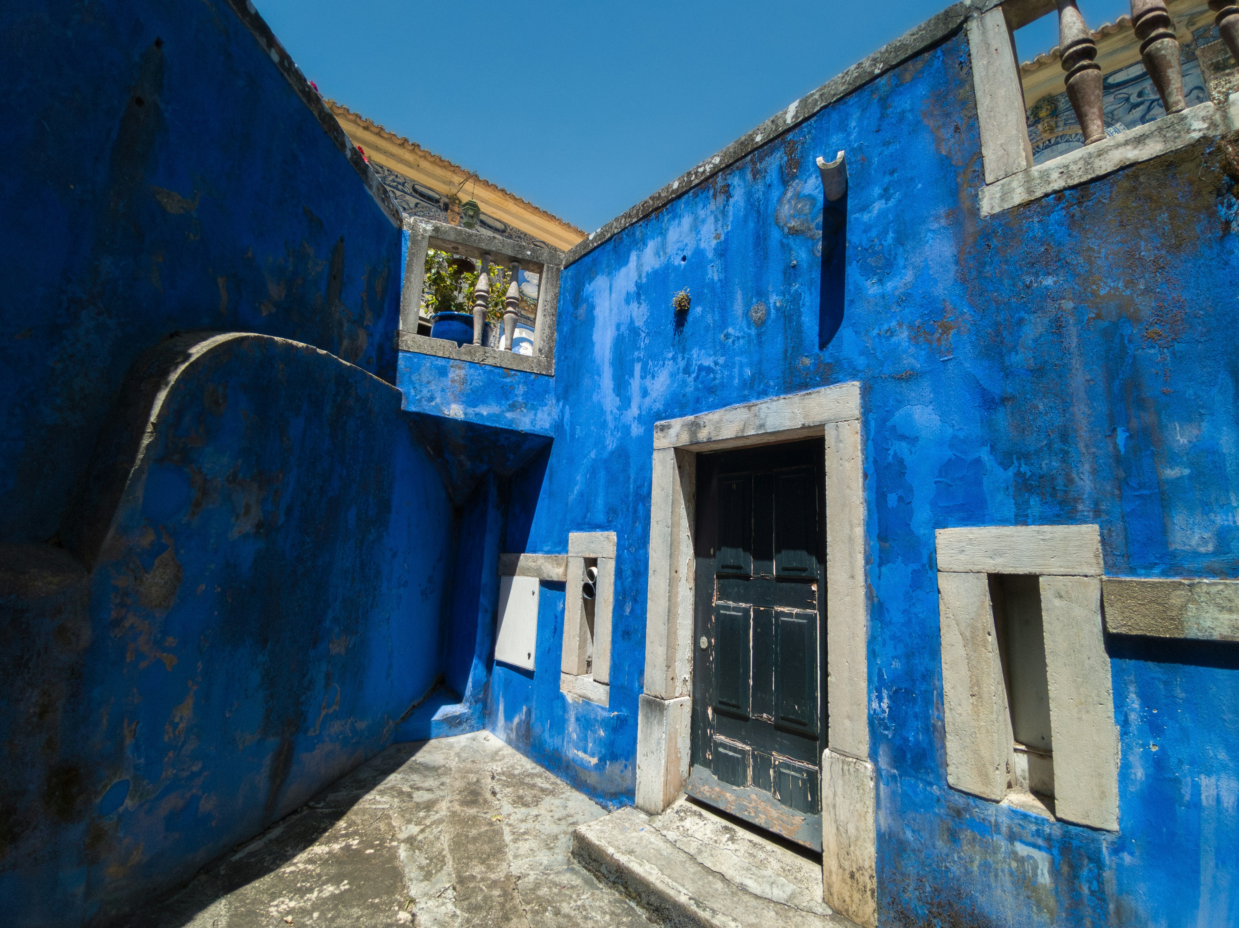 Schmale Gasse zwischen leuchtend blauen Gebäuden mit einer dunklen Tür.