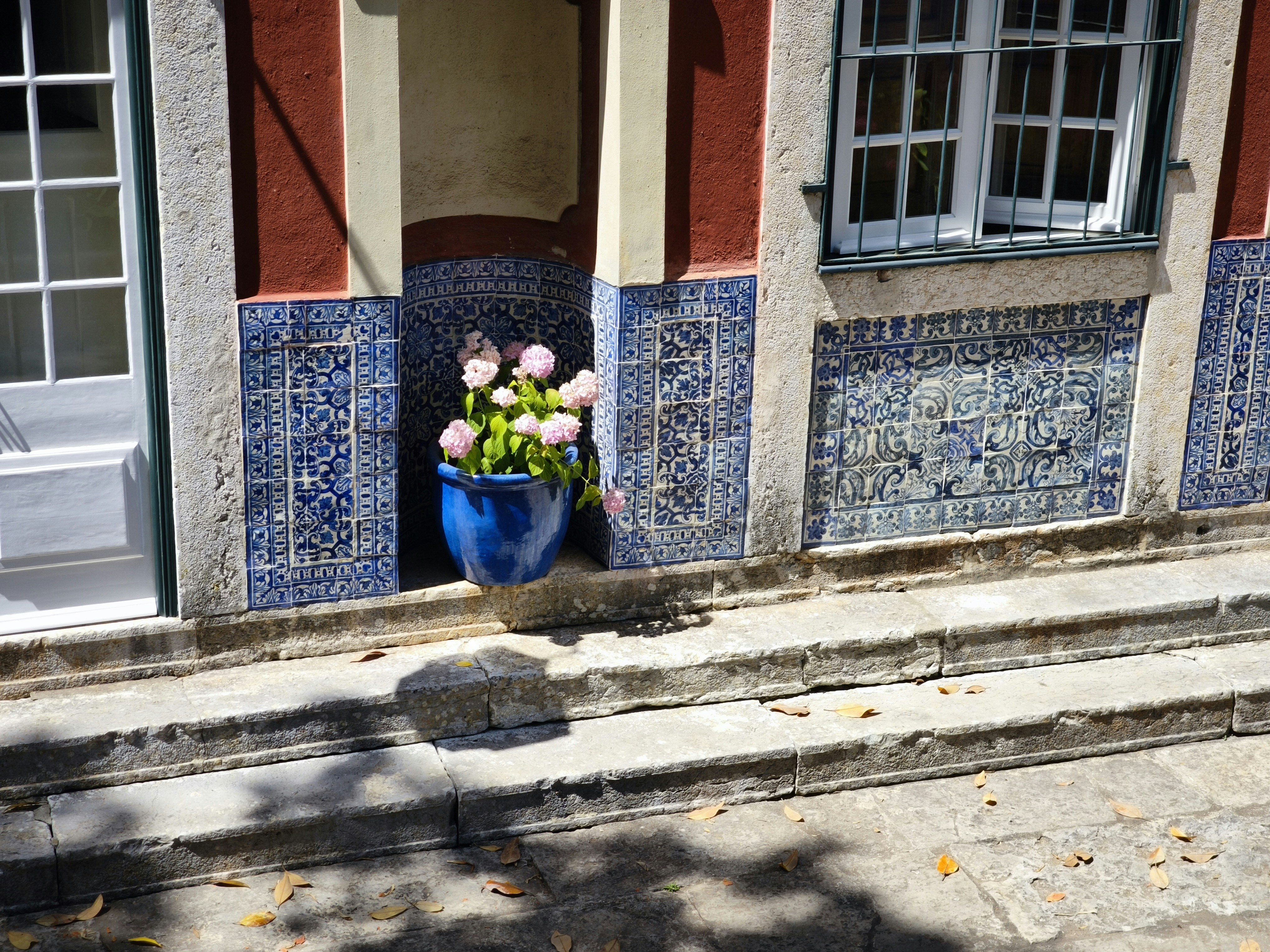 Historische Gebäudefassade mit blauen Fliesen und rosa Blumen.