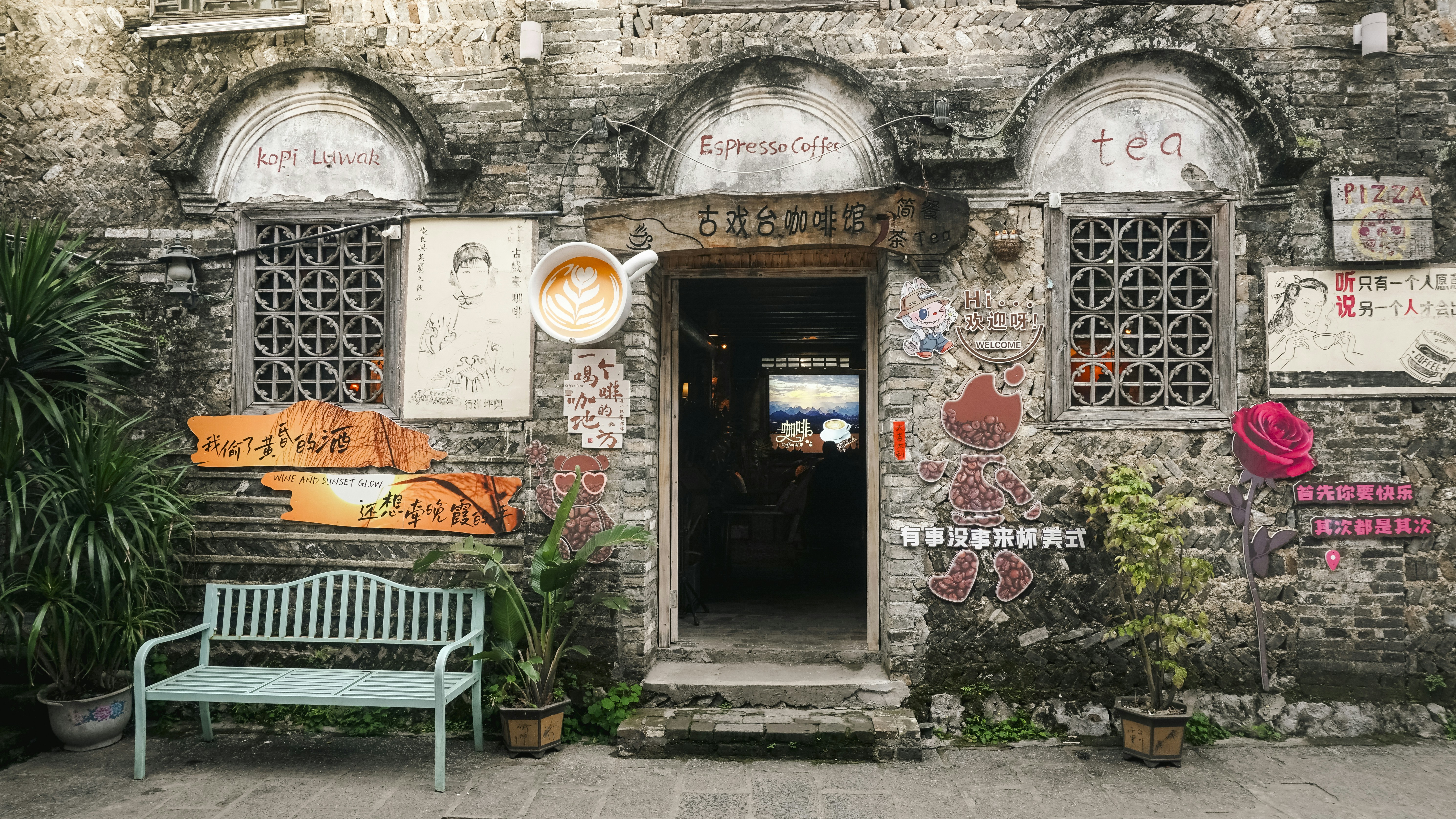 Rustic stone building facade with open door and blue bench.
