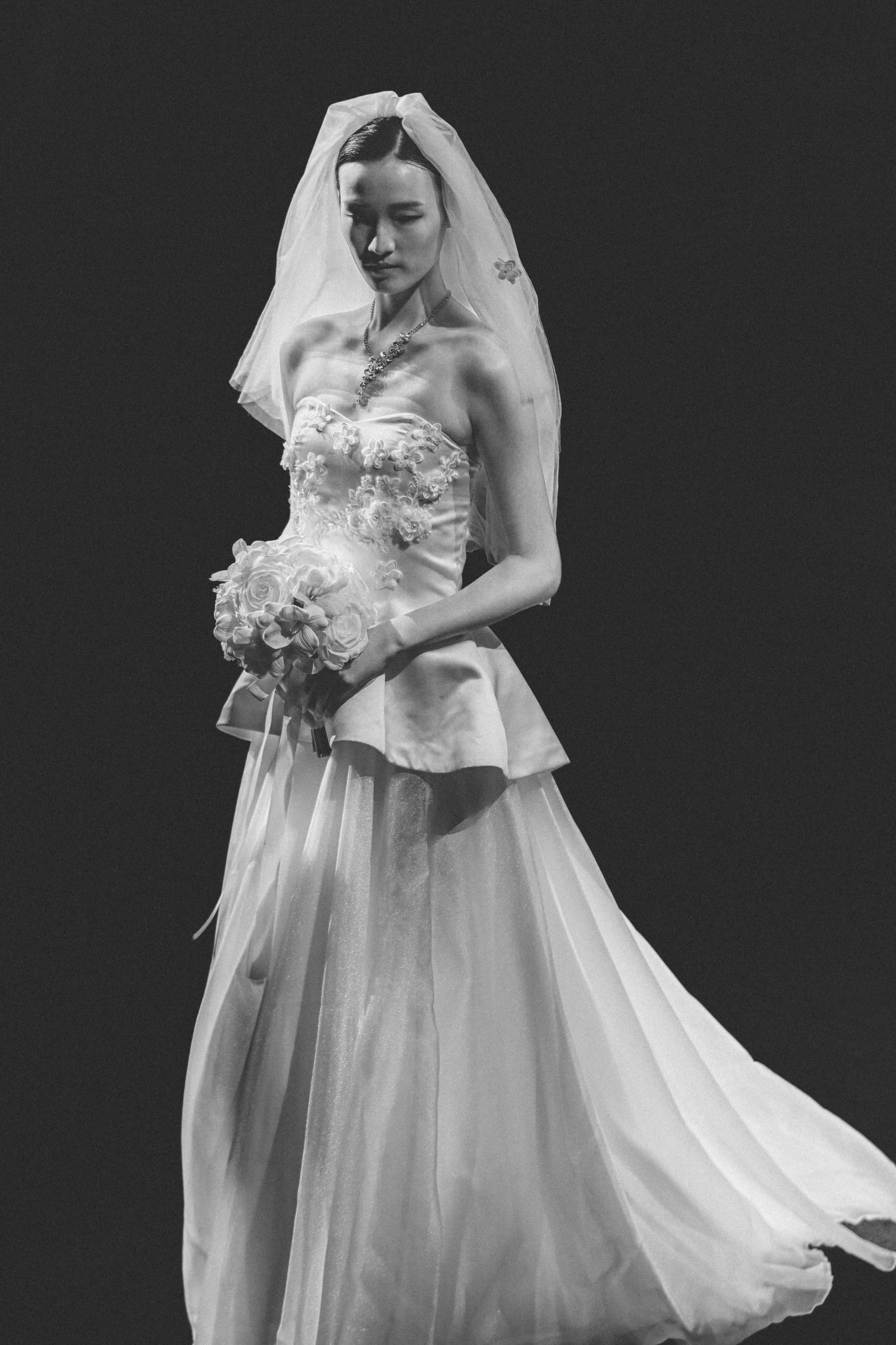 Woman in wedding dress with veil and bouquet.