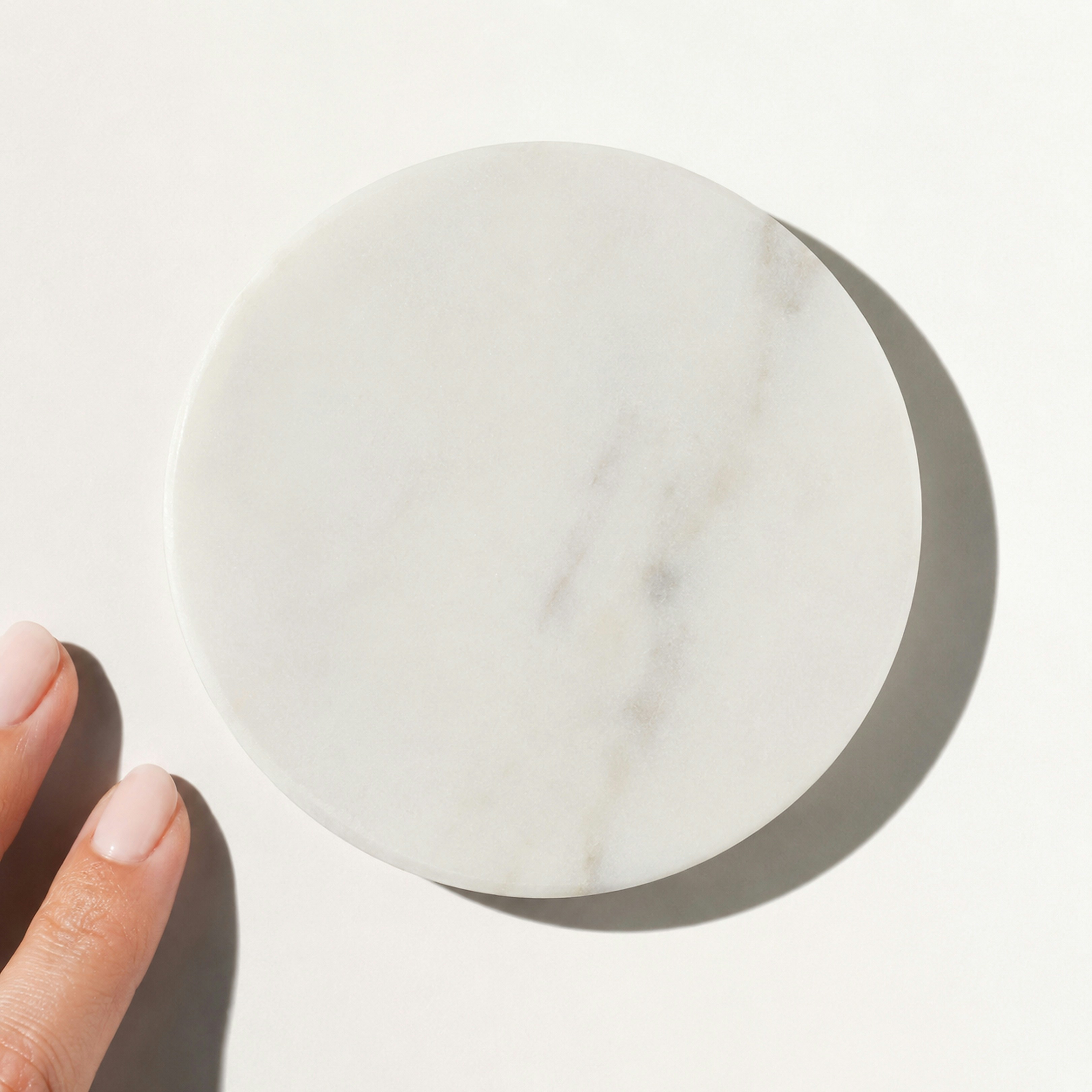 A round white marble coaster on a white surface