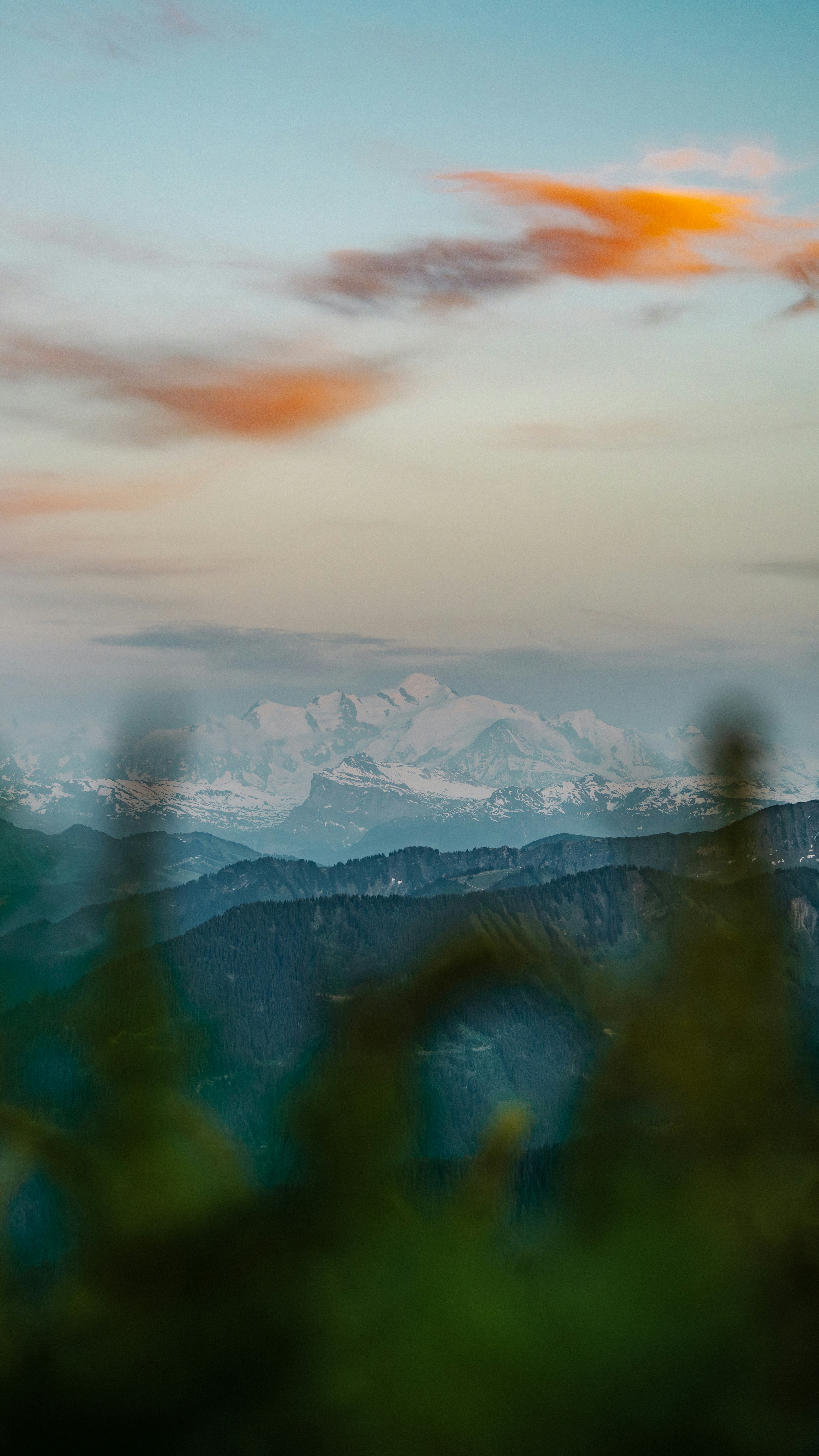 Scenic view of snow-capped mountains and layered hills at dusk.