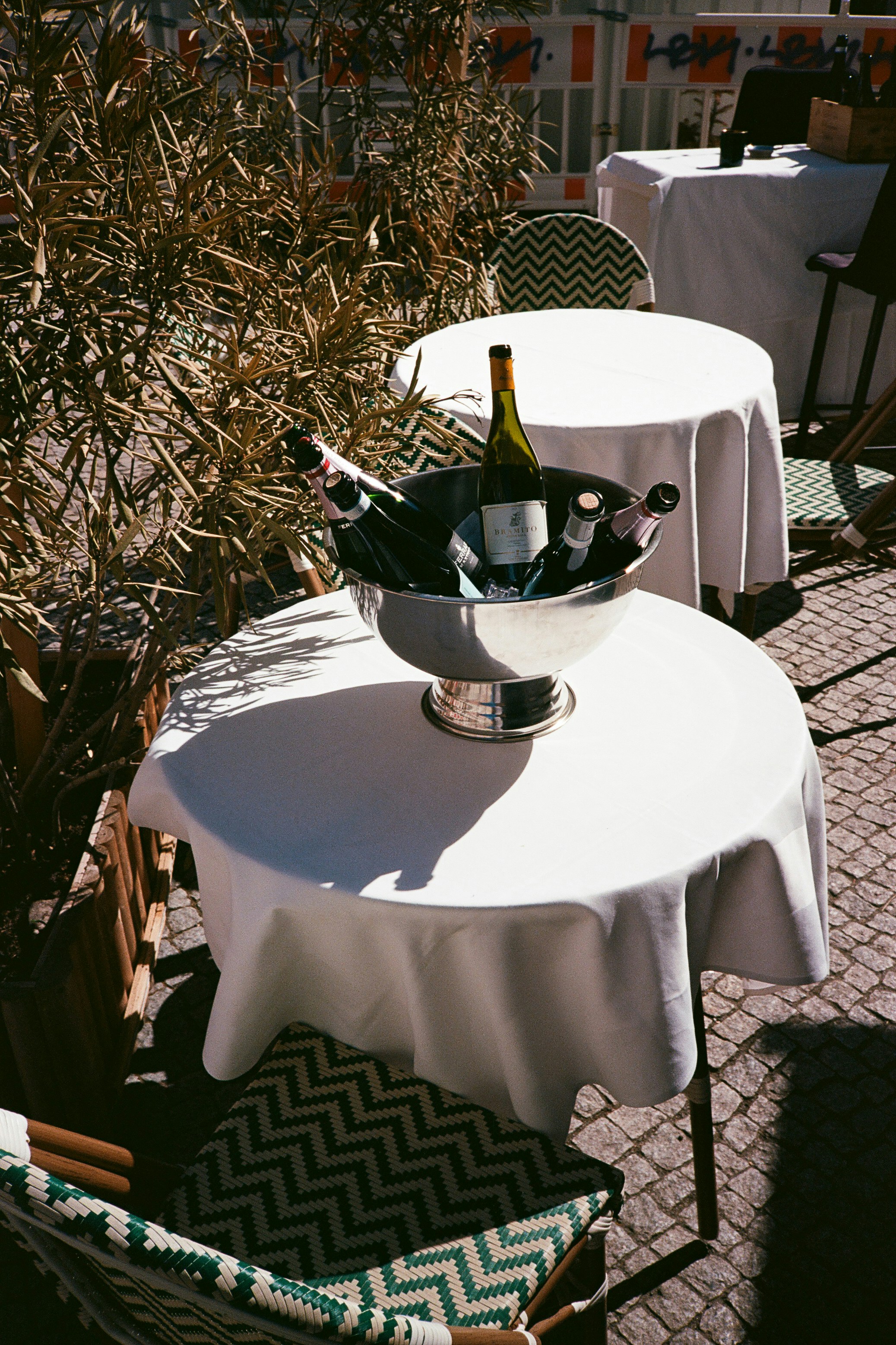 Ein Cafétisch im Freien mit einem Champagnereimer und Flaschen.