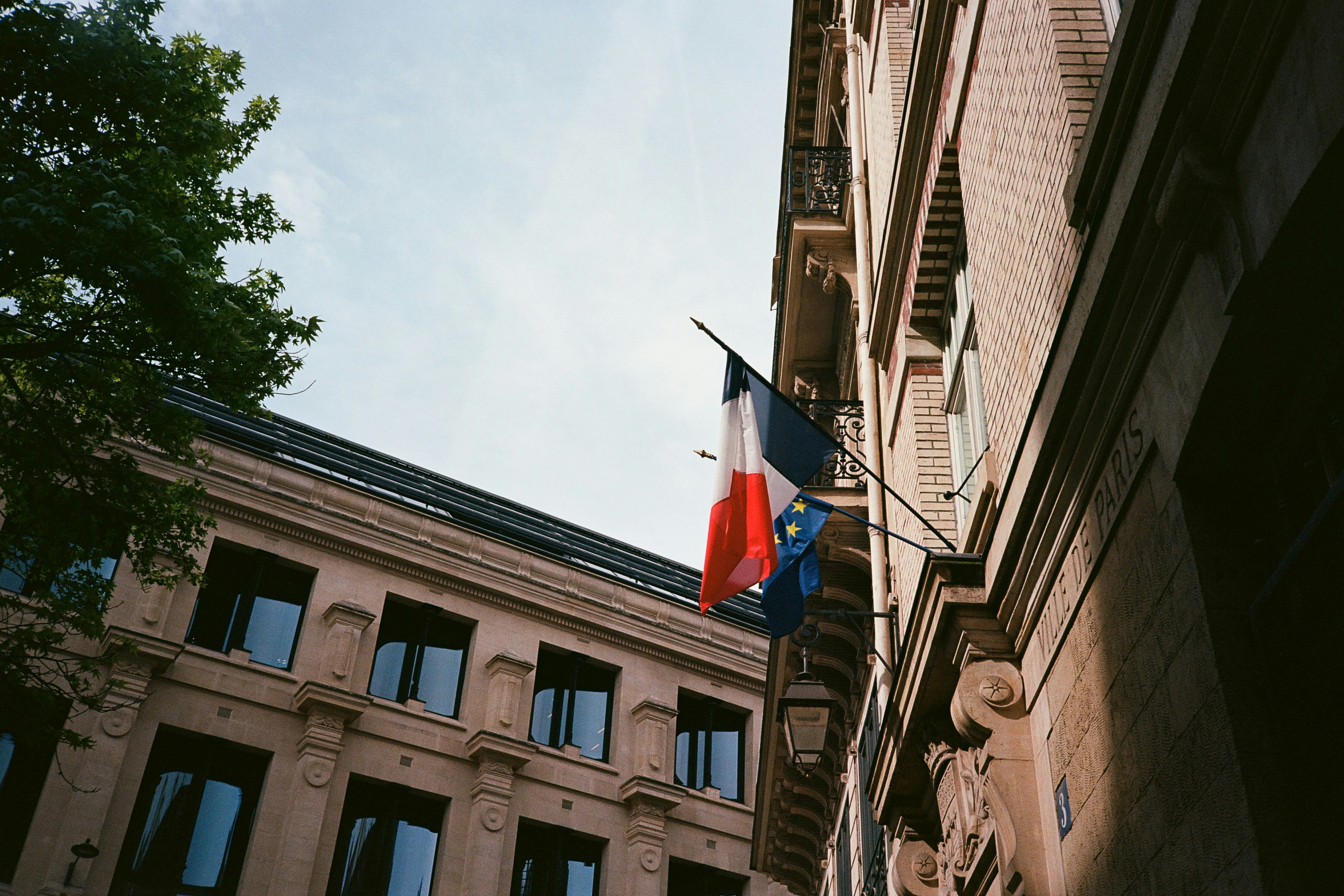 Französische und EU-Flaggen wehen an einem alten Gebäude.